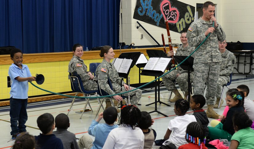 U.S. Army Spc. Andrew Moon, U.S. Army Training and Doctrine Command Band instrumentalist, demonstrates the full length of a French horn with Zymir Mitchell, age 7, during a performance at George J. McIntosh Elementary School in Newport News, Va., March 16, 2015. Band members taught children about each of their instruments and basic musical styles as part of a month-long tour throughout Hampton Roads area schools. (U.S. Air Force photo by Staff Sgt. Teresa J. Cleveland/Released)