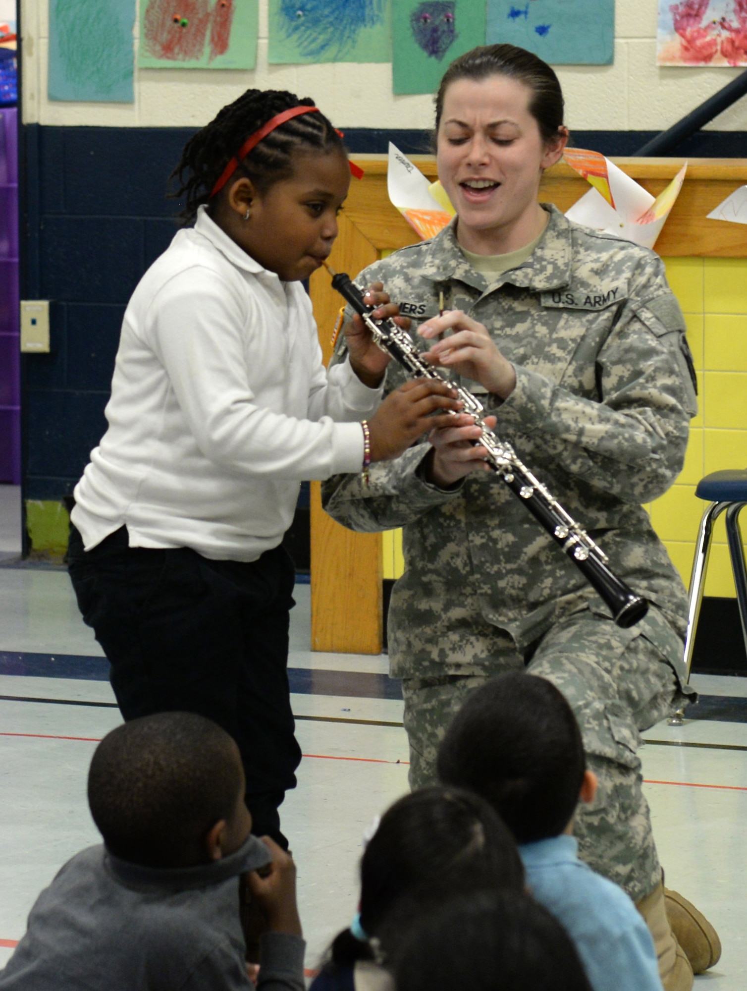 U.S. Army Spc. Alicia Cathers, U.S. Army Training and Doctrine Command Band instrumentalist, helps Niya Rashko, age 6, demonstrate how to play an oboe during a performance at George J. McIntosh Elementary School in Newport News, Va., March 16, 2015. The performance team members taught the children about music, including different instruments and how they work, and their careers as Army musicians. (U.S. Air Force photo by Staff Sgt. Teresa J. Cleveland/Released)