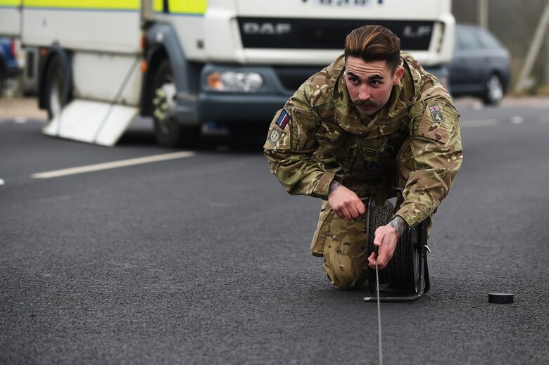 Royal Air Force Senior Aircraftsman Technician Zac Herdman, with the 5131 Bomb Disposal Squadron at RAF Wittering, rolls a wire back from the RAF Alconbury, England large vehicle inspection gate during a training exercise, March, 17, 2015. Both UK and U.S. Service members were able to implement hands-on training when responding to the simulated-hazardous incident. (U.S. Air Force photo by Staff Sgt. Jarad A. Denton/Released)