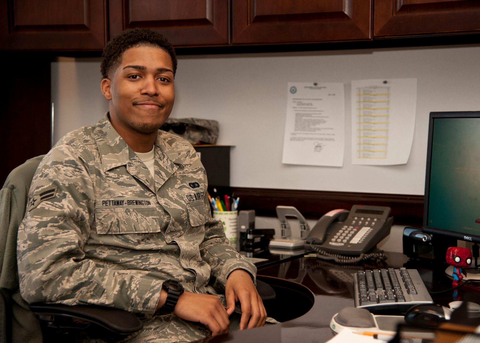 PETERSON AIR FORCE BASE, Colo. – Airman 1st Class Aaron “PB” Pettaway-Brewington, 21st Wing Staff Agency executive command section admin, poses for a photo at his desk. In additional to his daily duties, he is the WSA functional area records manager, which requires thorough diligence ensuring each of the Wing’s 16 staff agencies’ records are up-to-date, organized and always inspection ready. (U.S. Air Force photo/Staff Sgt. J. Aaron Breeden)