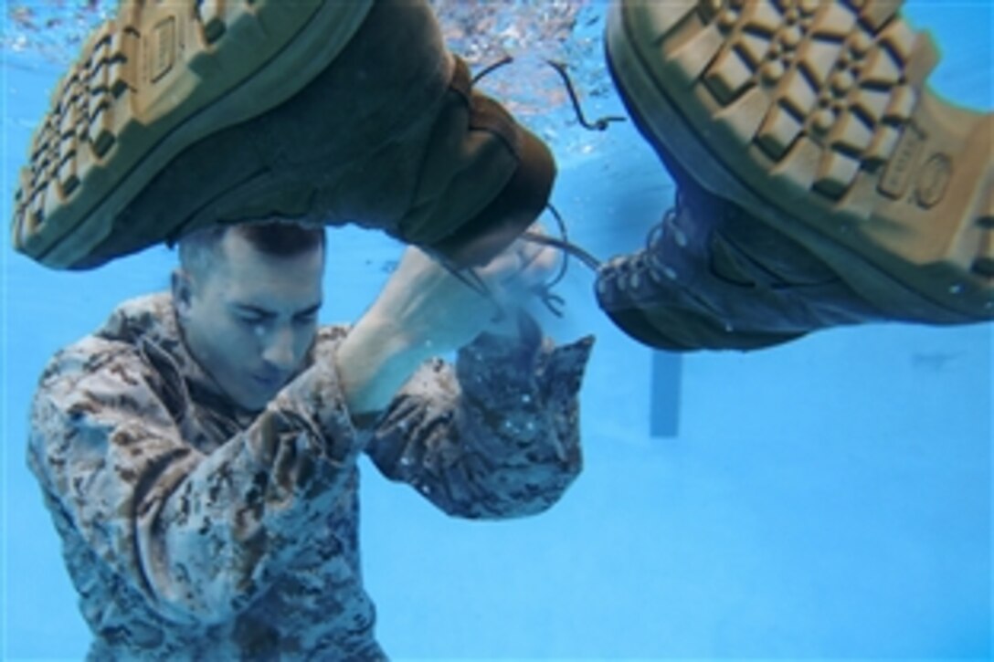 Marine Corps Sgt. Nicholas P. Slover removes his boot before inflating his pants during a swim qualification course on Marine Corps Base Camp Lejeune, N.C., March 17, 2015. Marines must tread water for 10 minutes during the qualification to demonstrate they can properly use their uniform as a flotation device for survival in water. 

