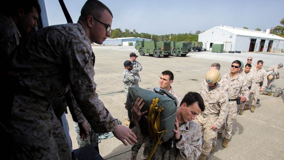 Students wait in line to receive main and reserve parachutes in preparation for a static-line jump during a jumpmaster course at Bogue Airfield, Bogue, N.C., March 11, 2015. Army instructors from Fort Benning, Ga., came to Camp Lejeune to teach Marines what they need to know to be a jumpmaster, including how to perform personnel inspections, how to react to certain malfunctions and how to jump with several types of equipment.