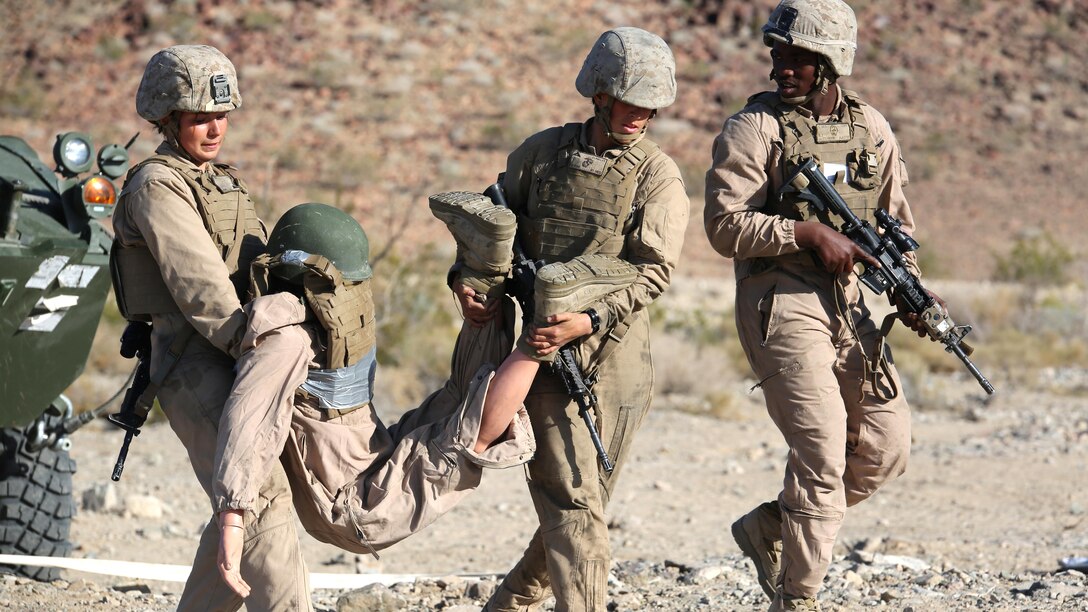Lance Corporals Brittany R. Dunklee, left, gunner, and Ashleigh Howell, center, driver, both with Light Armored Vehicle Platoon, Company B, Ground Combat Element Integrated Task Force, carry a simulated casualty while Cpl. Benjamin Alexander, right, vehicle commander, provides security, during the CASEVAC  portion of a Marine Corps Operational Test and Evaluation Activity assessment at Range 500, Marine Corps Air Ground Combat Center Twentynine Palms, California, March 12, 2015. From October 2014 to July 2015, the GCEITF will conduct individual and collective level skills training in designated ground combat arms occupational specialties in order to facilitate the standards-based assessment of the physical performance of Marines in a simulated operating environment performing specific ground combat arms tasks.