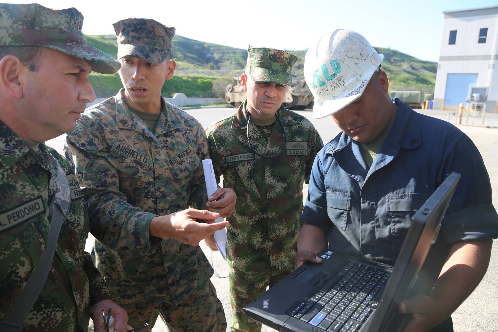 Sergeant Juan Arguello, center, an Engineer Equipment Mechanic with 1st Maintenance Battalion, Combat Logistics Regiment 15, 1st Marine Logistics Group, explains current computer software procedures to Lt. Col. Andres Perdomo, the Chief of Logistics for the Colombian Marine Corps, during a three-day tour around Combat Logistics Regiment 15, 1st Marine Logistics Group, aboard Camp Pendleton, California, March 3, 2015. Perdomo and Lt. Col. Ferdando Fernandez, a Battalion Commander for the Support Command, 6th Infantry Brigade, Colombian Marine Corps, visited 1st MLG to allow members of both the U.S. Marine Corps and Colombian Armed Forces to build an understanding of services, share best practices and strengthen camaraderie and interoperability. (U.S. Marine Corps photo by Sgt. Cody Haas/Released)