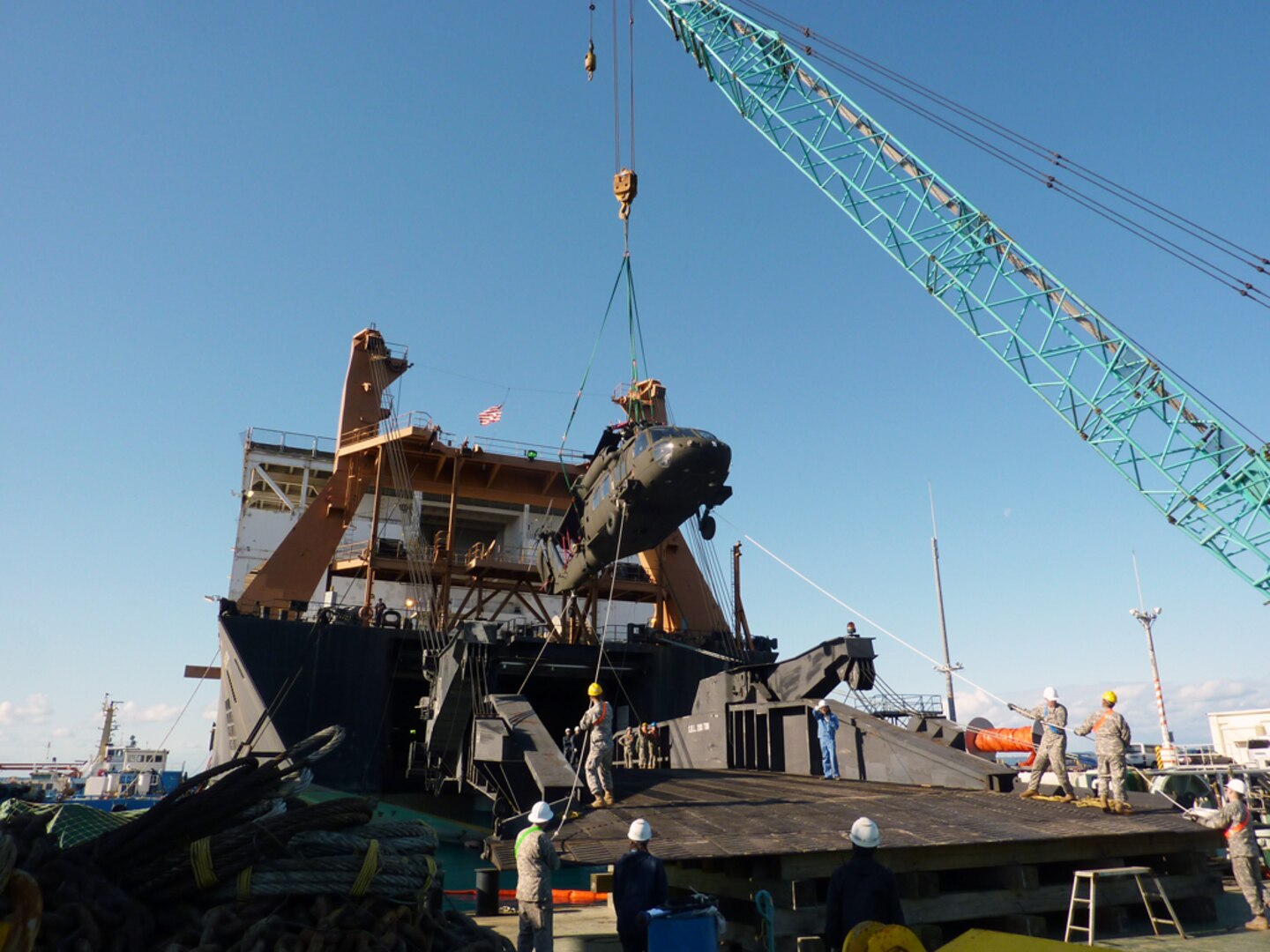 In this file photo, transportation Battalion Members of the 835th Transportation Battalion, Soldiers, and contractors offload a helicopter using a shore crane from the USNS Sgt. Matej Kocak's stern ramp supported by a platform they built on a barge during port operations Feb. 9-12.