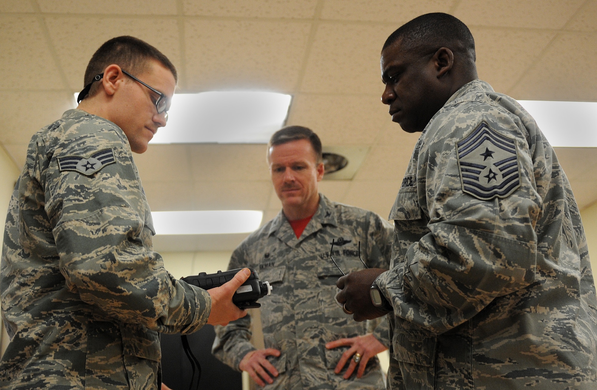 Senior Airman Cody Henning, 8th Civil Engineer Squadron readiness and emergency management journeyman, shows Col. Ken “Wolf” Ekman, 8th Fighter Wing commander, and Chief Master Sgt. Lee “Wolf Chief” Barr, 8th Fighter Wing command chief, how to check chemical threats in the air using hazardous material equipment at Kunsan Air Base, Republic of Korea, March 13, 2015. Henning showed Wolf and Wolf Chief how he contributes to the Wolf Pack mission. (U.S. Air Force photo by Senior Airman Divine Cox/Released) 