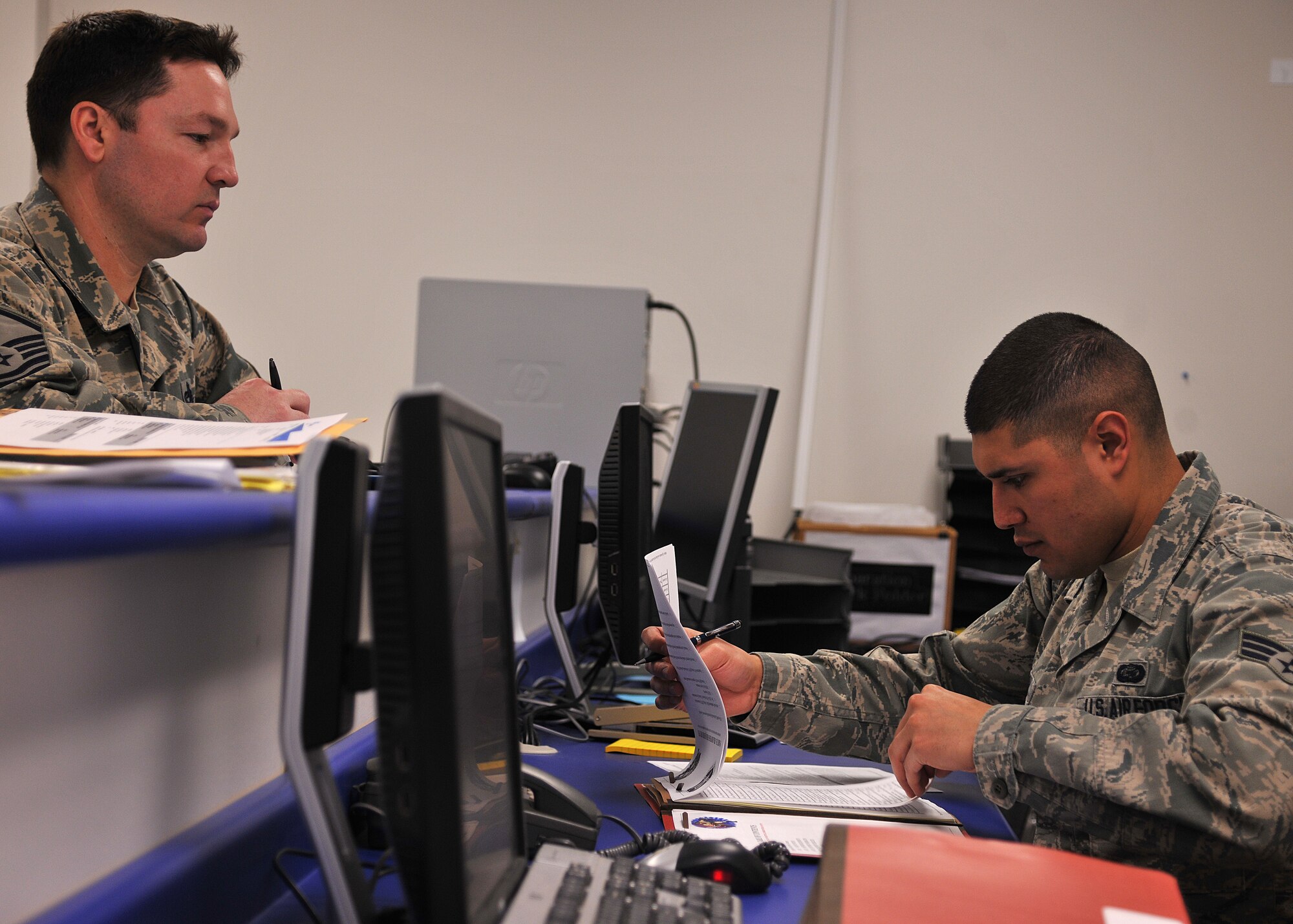 (Right) Senior Airman Maximilliano Estrada, 319th Force Support Squadron installation readiness technician, inspects a mobility folder for correct documents during an outprocessing checkpoint on March 19, 2015, on Grand Forks Air Force Base, N.D. Estrada was selected as the Grand Forks AFB Warrrior of the Week for the third week of March 2015. (U.S. Air Force photo/Senior Airman Xavier Navarro)