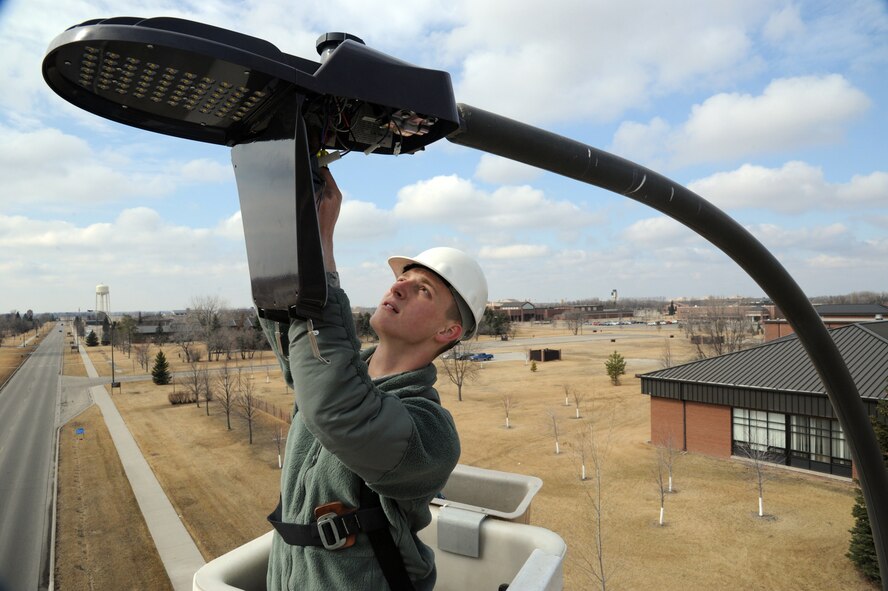 Airman 1st Class Ryan McClure, 319th Civil Engineer Squadron electrical systems apprentice, installs a new LED fixture on a streetlight on Grand Forks Air Force Base, N.D., March 19, 2015. The new fixtures are expected to use far less electricity than the previous high-pressure sodium bulbs. (U.S. Air Force photo/Staff Sgt. David Dobrydney)