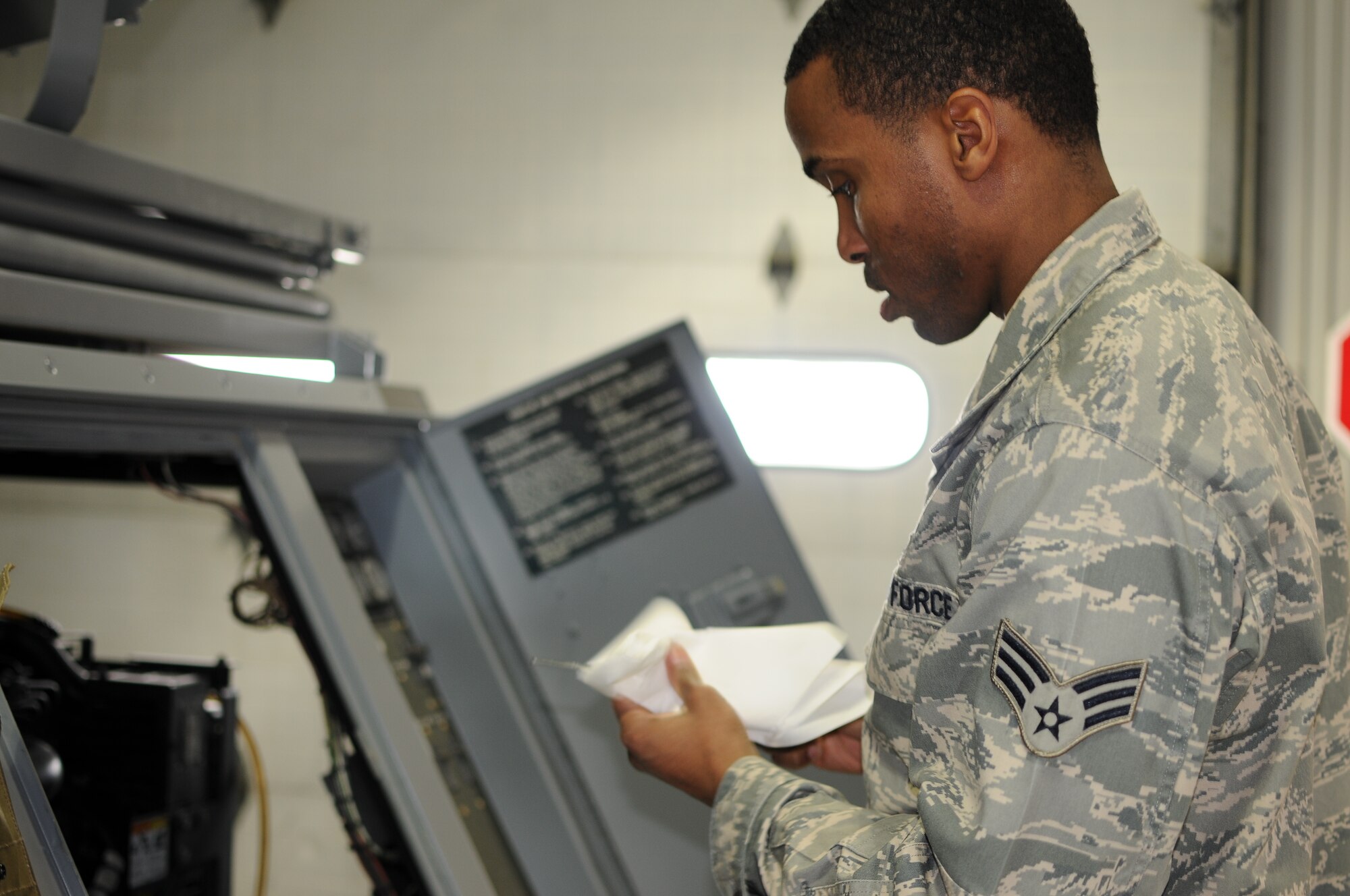 A picture of U.S. Air Force Senior Airman Gregory Gilkes checking a light cart's oil level.