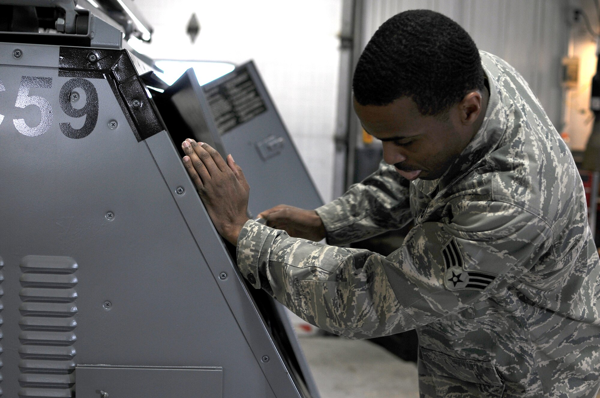 A picture of U.S. Air Force Senior Airman Gregory Gilkes, from the New Jersey Air National Guard's 177th Fighter Wing in Egg Harbor Township, N.J., inspecting the hinges and latches on a light cart.