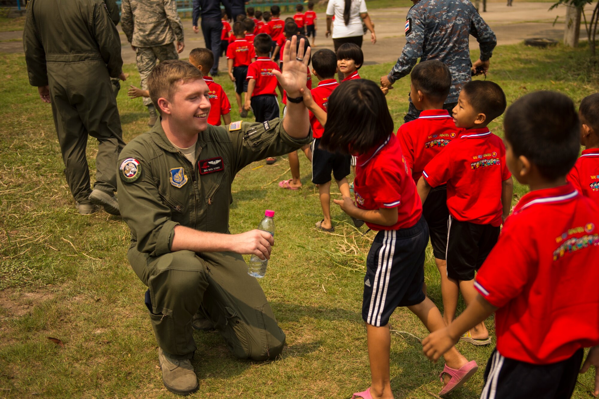 U.S. Air Force Senior Airman Nick Kenny high-fives children during a visit to a local boys and girls shelter in Udon Thani, Thailand, March 18, 2015. CT15 includes 22 total flying units and over 1390 personnel from three countries and continues the growth of strong, interoperable, and beneficial relationships within the Asia-Pacific region through integration of airborne and land-based command and control assets.(U.S. Air Force photo by Airman 1st Class Taylor Queen/Released)