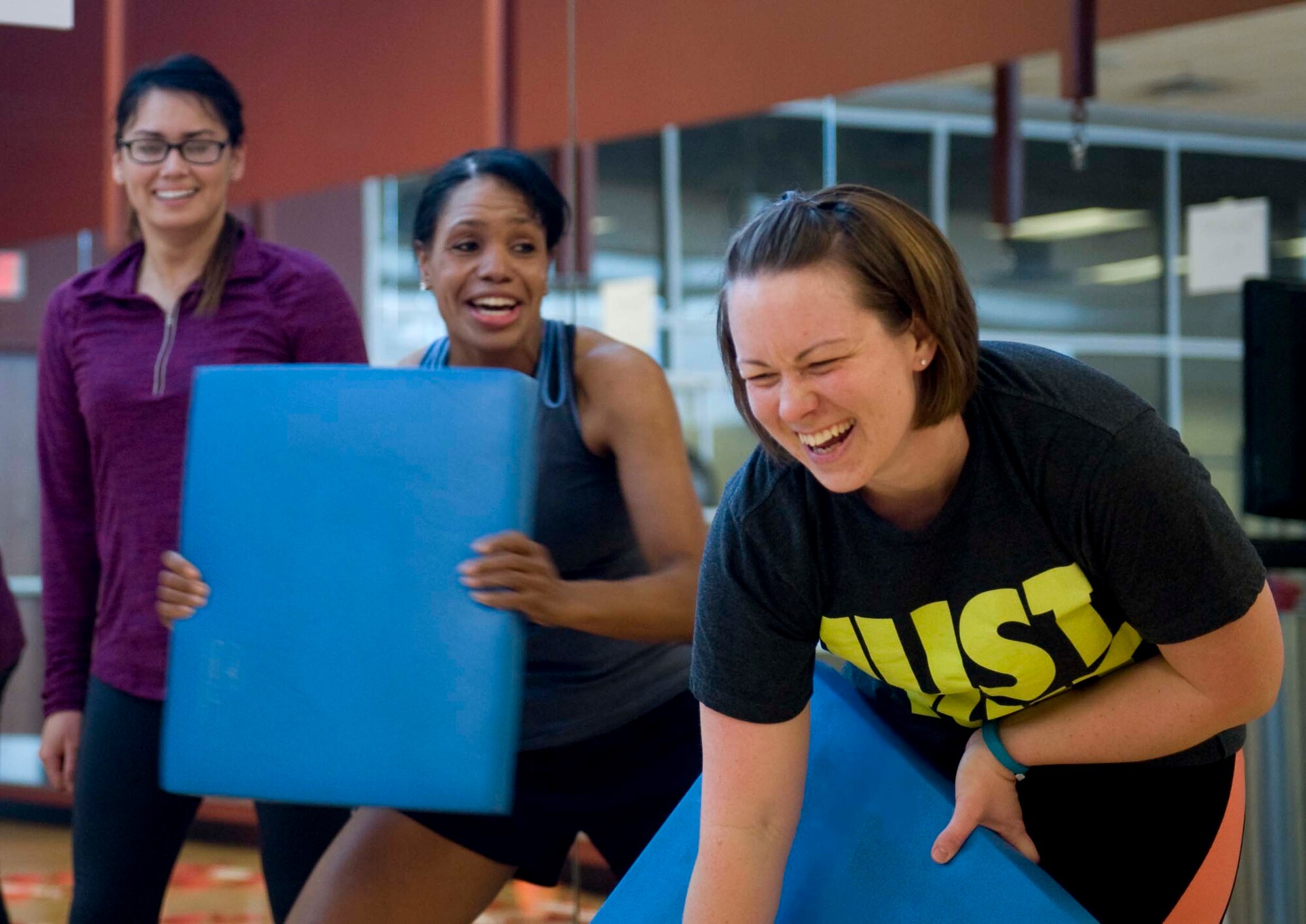 Tech. Sgt. Amanda Cook (right), 99th Civil Engineer Squadron unit training manager, has a laugh with Warrior Fitness Center  fitness instructor, Nikki Harris (center) as they perform punches during a Warrior Challenge Soar into Shape class at the fitness center on Nellis Air Force Base, Nev., Feb. 25, 2015. Harris has adopted a boisterous teaching style of which inspires those she teaches to do their very best. (U.S. Air Force photo by Airman 1st Class Rachel Loftis)