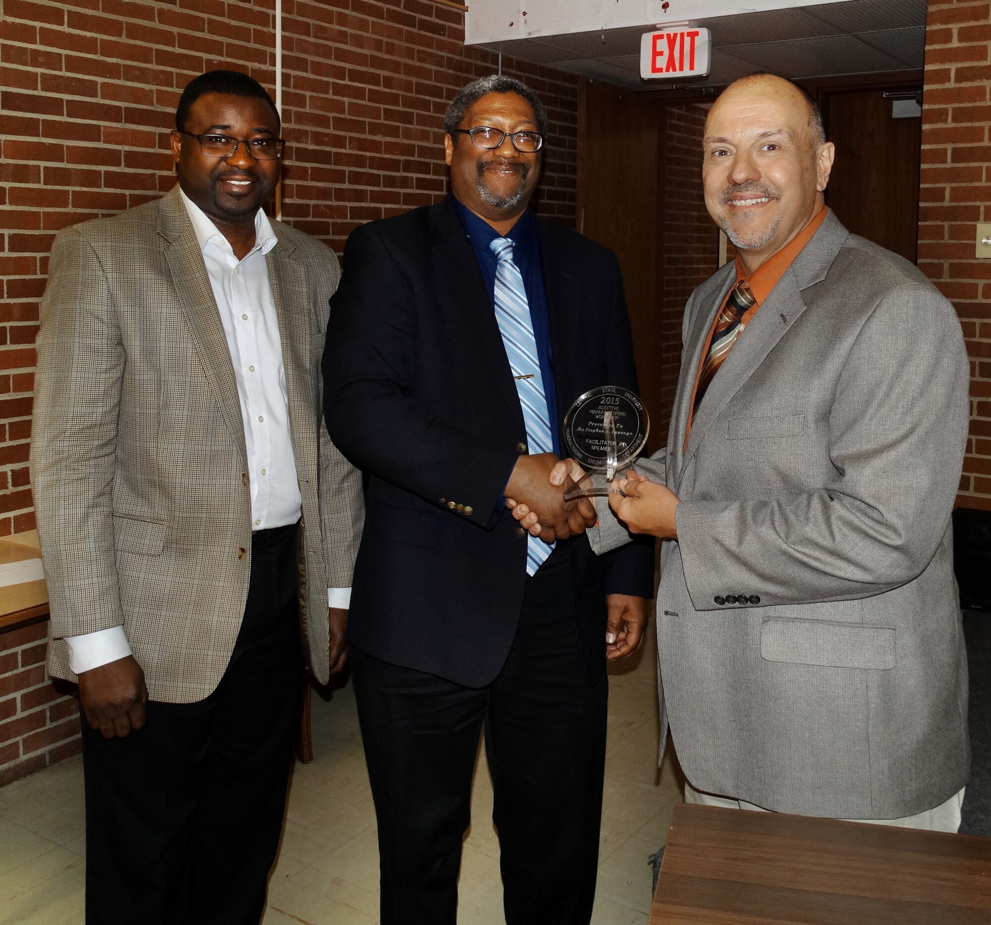 Stephen Szaruga (right), Chief Engineer of the Manufacturing and Industrial Technologies Divison of the AFRL Materials and Manufacturing Directorate, is presented a memento by Dr. Abiodun Fasoro (left) and Dr. Augustus Morris of Central State University. Szaruga spoke to attendees at the March 5, 2015 Additive Manufacturing Workshop. (Photo by Tobey Cordell. Universal Technology Corporation)