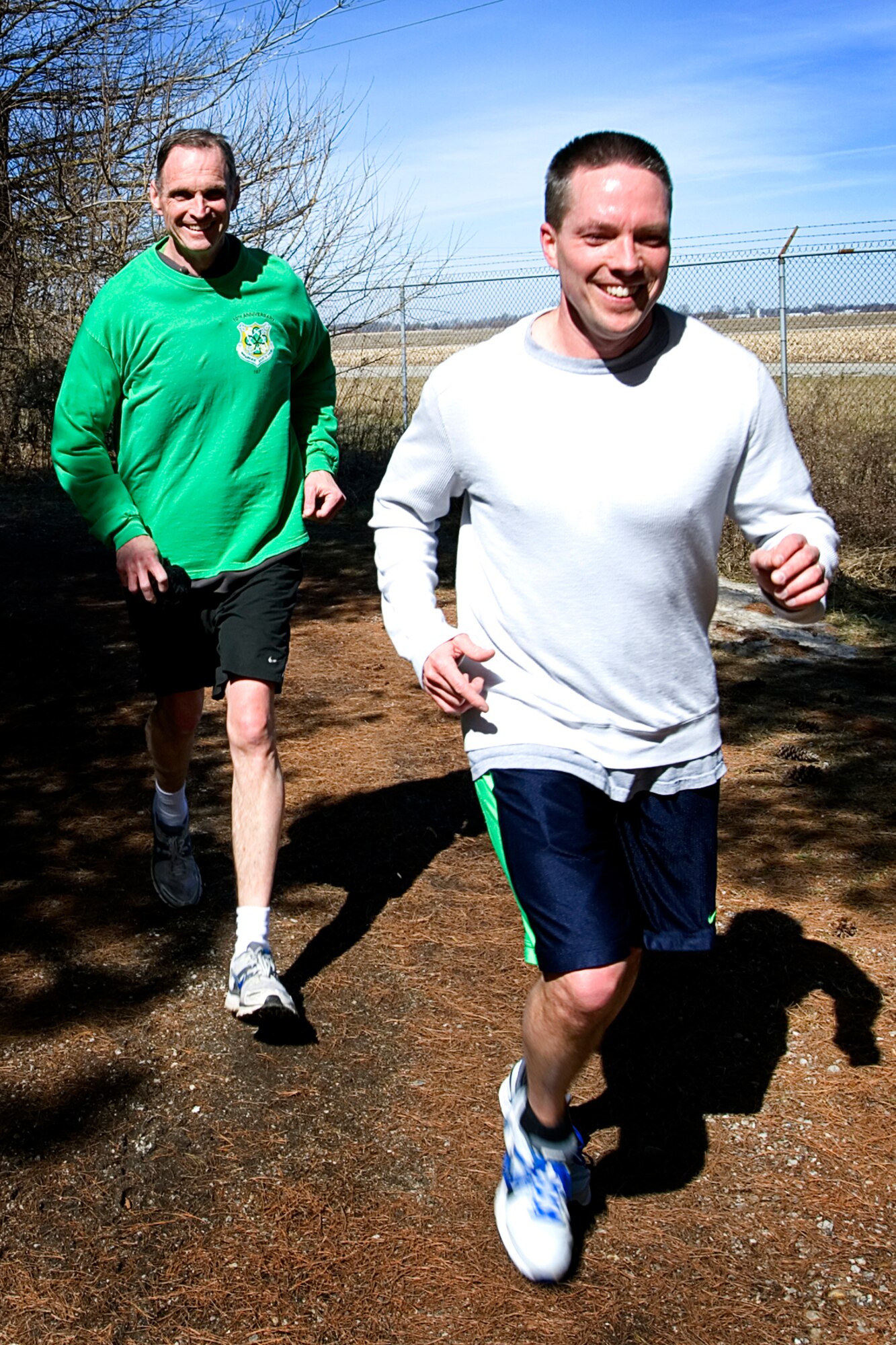 Clint Kiehl, right, and Marty Foye, both 434th Air Refueling Wing finance officers, round the northwest corner of the base heading into the shady pine tree area of the running trail at Grissom Air Reserve Base, Ind., March 18, 2015. The two participated in a St. Patrick's Day 8K run sponsored by the fitness center. (U.S. Air Force photo/Tech. Sgt. Douglas Hays)