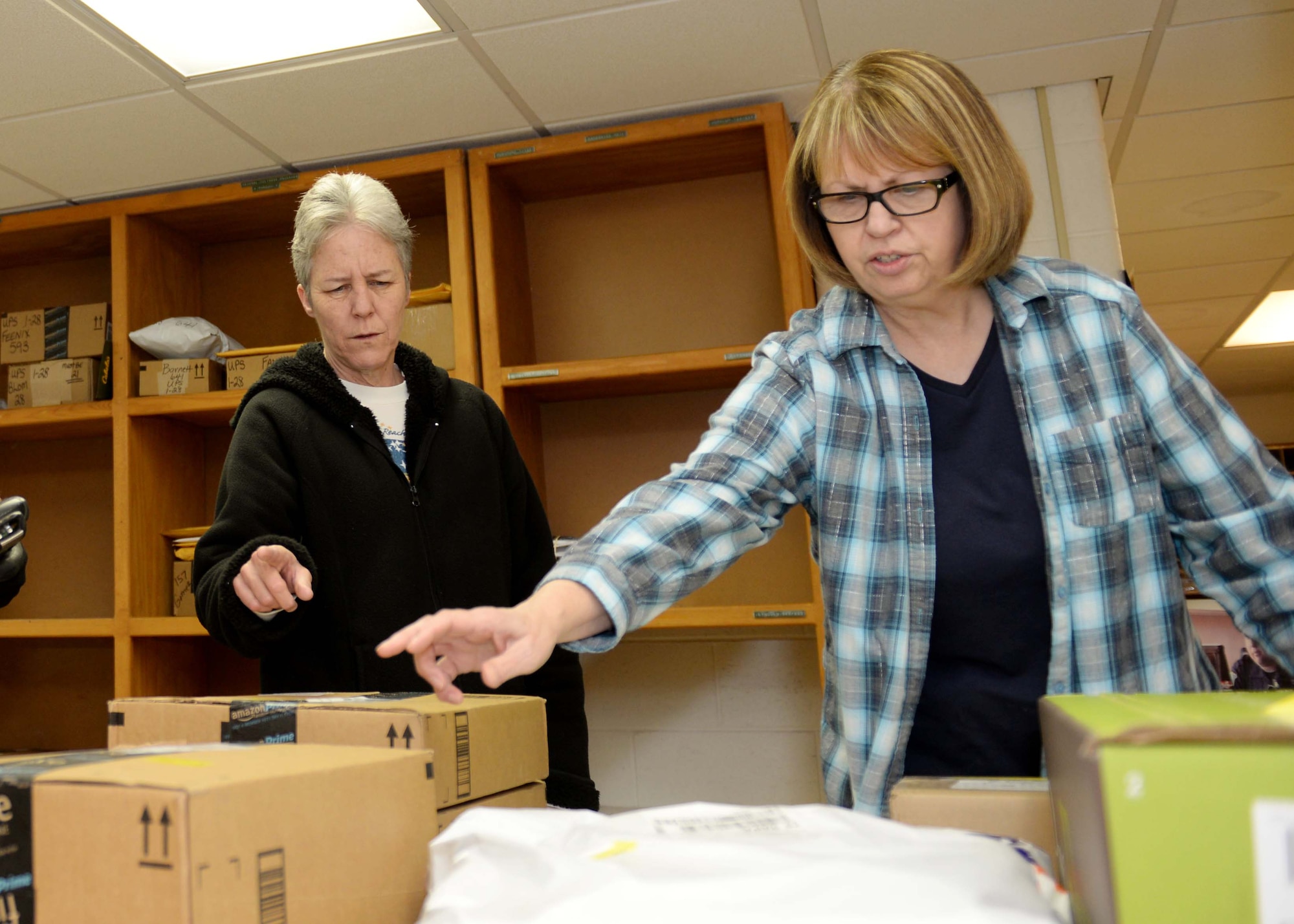 Lori Steever, 28th Communications Squadron postal service center manager (right), and Renee Griffith, 28th CS PSC clerk, organize packages at the Postal Service Center at Ellsworth Air Force Base, S.D., Jan. 28, 2015. Ellsworth’s PSC is run by Lori Steever, Griffith and Darla Steever, 28th CS PSC clerk, who work year-round delivering mail to dorm Airmen. (U.S. Air Force photo by Airman 1st Class Rebecca Imwalle/Released)
