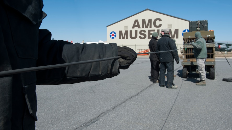 Staff Sgt. Allan Flores, 436th Civil Engineer Squadron electrician, holds onto an electrical cable as it is being wound up March 18, 2015, at Dover Air Force Base, Del. Upon completion of inspection, all of the electrical cables were wound back up for storage. (U.S. Air Force photo/Airman 1st Class Zachary Cacicia)