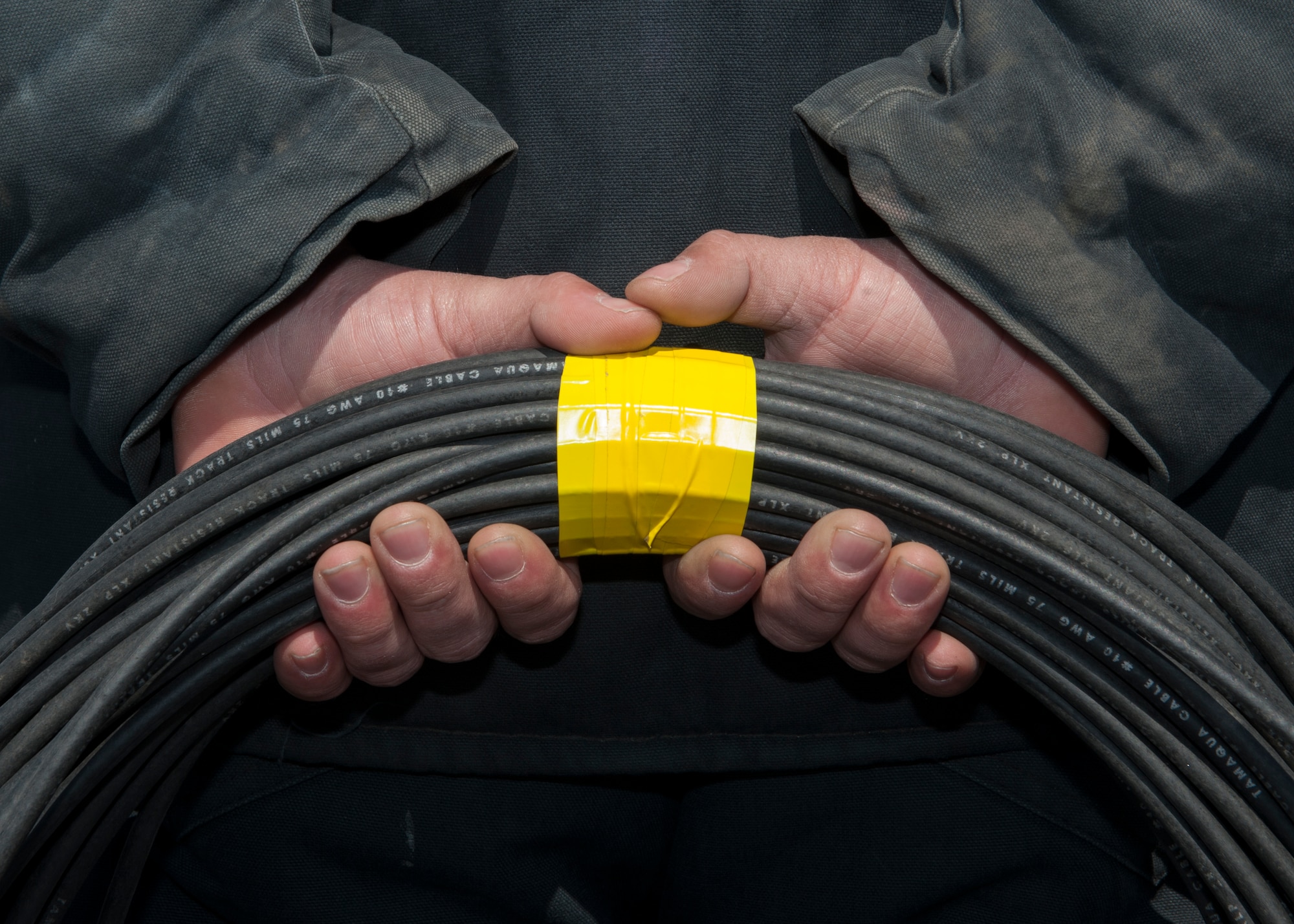 Senior Airman Joseph Walters, 436th Civil Engineer Squadron electrician, holds a coiled electrical cable, March 18, 2015, at Dover Air Force Base, Del. These cables are part of the Emergency Airfield Lighting System. (U.S. Air Force photo/Airman 1st Class Zachary Cacicia) 