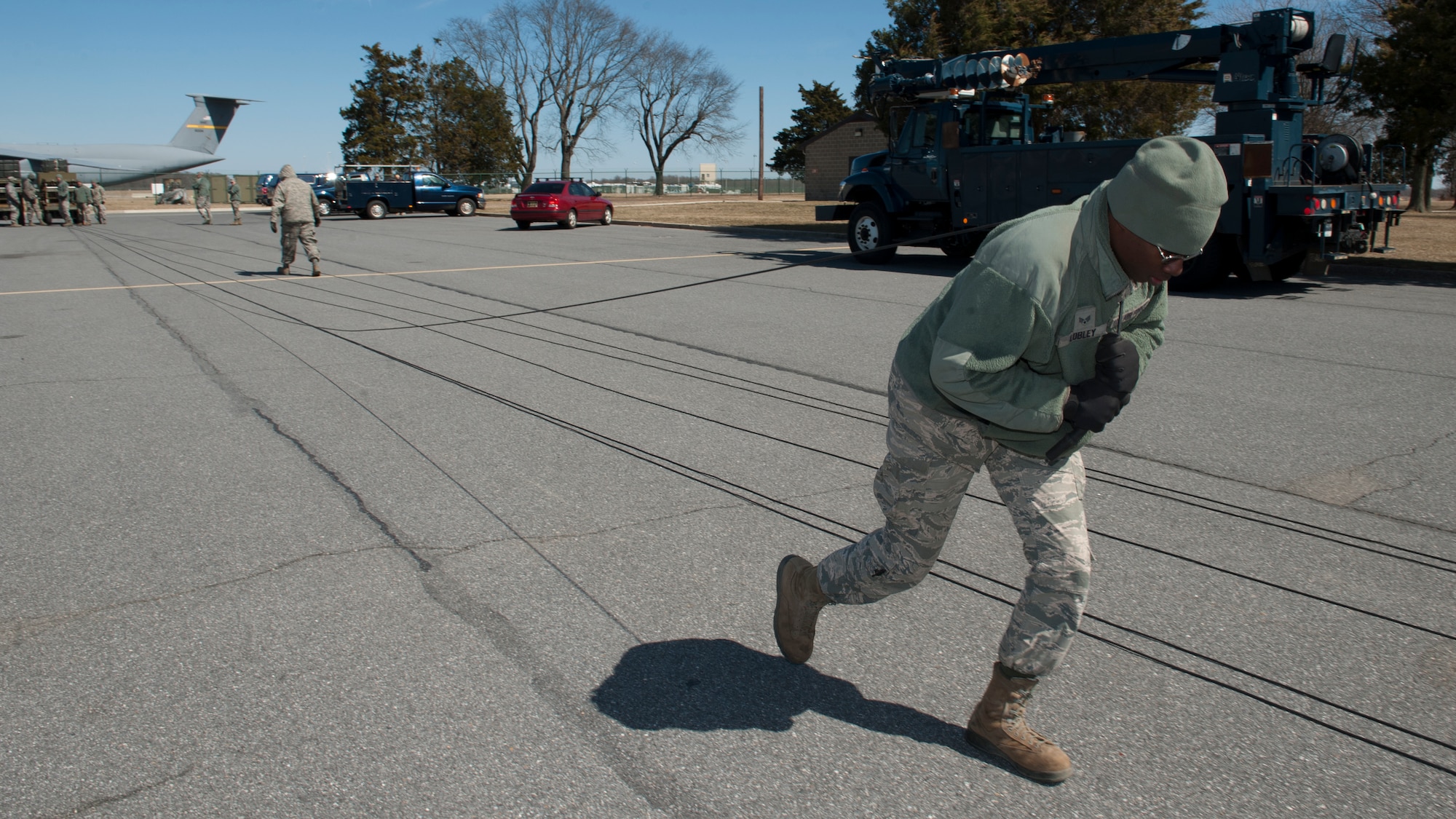 Senior Airman Roderick Lobley, 436th Civil Engineer Squadron electrician, pulls an electrical cable over his shoulder March 18, 2015, at Dover Air Force Base, Del. The cables are part of the Emergency Airfield Lighting System. (U.S. Air Force photo/Airman 1st Class Zachary Cacicia)