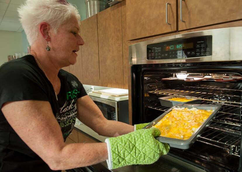 Dawne Nickerson-Banez, 436th Mission Support Group honorary commander, pulls a tray of shepherd’s pie out of an oven March 17, 2015, at Dover Air Force Base, Del. The twice-a-month course has been organized by Nickerson-Banez since last April. (U.S. Air Force photo/Airman 1st Class Zachary Cacicia)