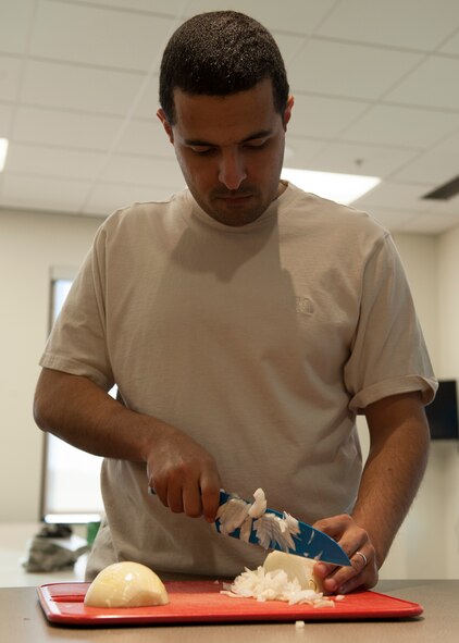 Senior Airman Alan Mejia, 436th Aerospace Medicine Squadron public health technician, dices an onion at a “Dorm to Gourm” class March 17, 2015, at Dover Air Force Base, Del. This class uses a hands-on method to teach Airmen cooking skills. (U.S. Air Force photo/Airman 1st Class Zachary Cacicia) 