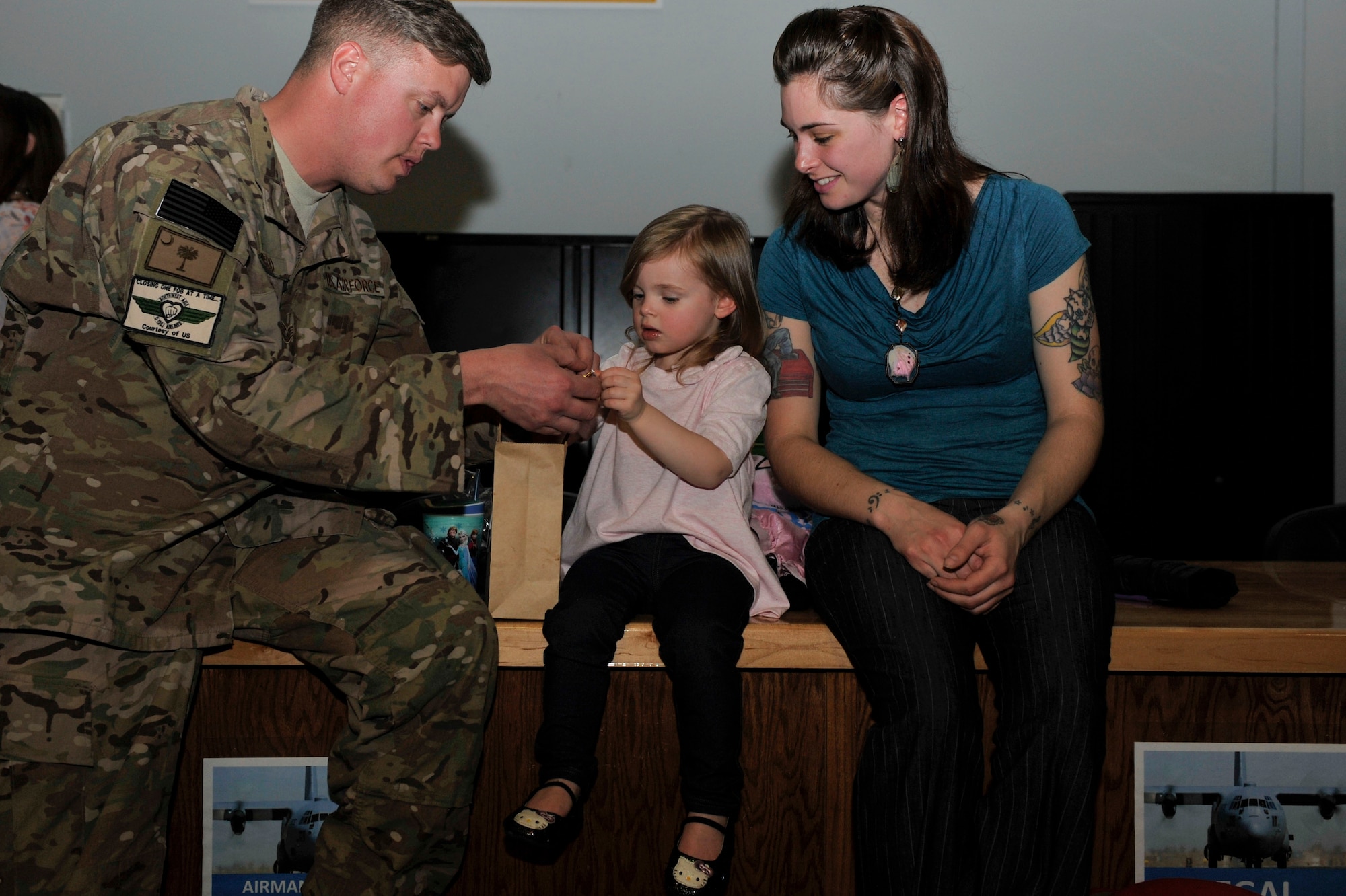Staff Sgt. William McLeod, a 314th Aircraft Maintenance Squadron crew chief, helps his daughter, Melody, 2, unwrap a piece of candy March 14, 2015, at Little Rock Air Force Base, Ark. The deployment was a true Team Little Rock effort as both the 314th Aircraft Maintenance Squadron and the 19th Maintenance Squadron maintainers deployed together in support of operations in Afghanistan. (U.S. Air Force photo by Senior Airman Regina Edwards)