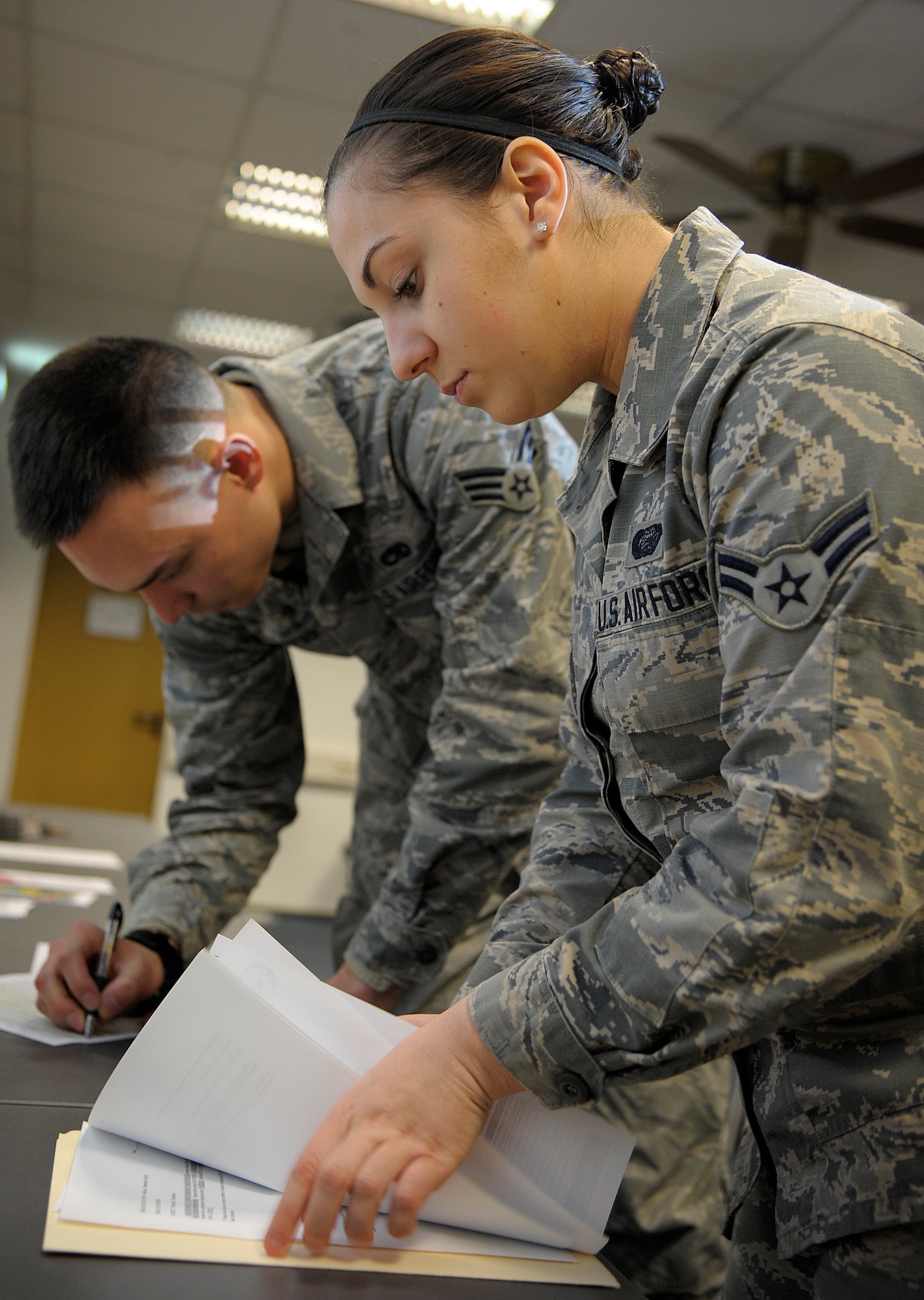 Airman 1st Class Danelle Oliver, 786th Force Support Squadron customer service technician, accepts paperwork from a base newcomer at Ramstein Air Base, Germany, March 12, 2015. Approximately 60 Airmen arrive to Ramstein weekly for in-processing. Upon arrival, one of the first steps they must complete is to be correctly gained into their new units. (U.S. Air Force photo/Senior Airman Timothy Moore)