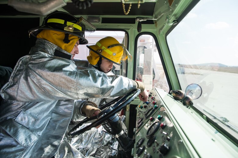 Senior Airman Scott Weeks, 52nd Civil Engineer Squadron firefighter, right, familiarizes Airman 1st Class Nathan Miller, 52nd CES firefighter, with the specific functions of a fire truck during down time at Campia Turzii, Romania, March 16, 2015. The firefighters joined More than 100 personnel and six F-16CJ Fighting Falcons in a bilateral Romanian and U.S. Air Force training event March 10 to 27. (U.S. Air Force photo/Staff Sgt. Armando A. Schwier-Morales)