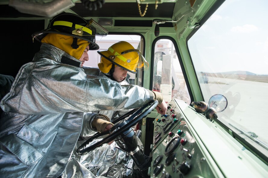 Senior Airman Scott Weeks, 52nd Civil Engineer Squadron firefighter, right, familiarizes Airman 1st Class Nathan Miller, 52nd CES firefighter, with the specific functions of a fire truck during down time at Campia Turzii, Romania, March 16, 2015. The firefighters joined More than 100 personnel and six F-16CJ Fighting Falcons in a bilateral Romanian and U.S. Air Force training event March 10 to 27. (U.S. Air Force photo/Staff Sgt. Armando A. Schwier-Morales)