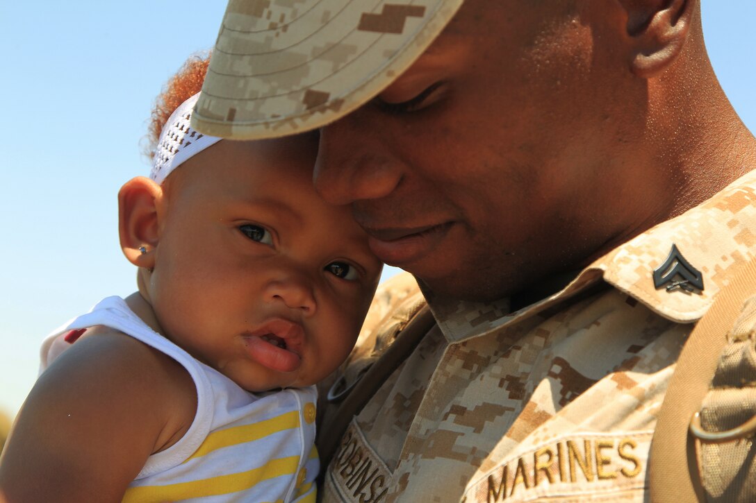 Marine Corps Cpl. Don Robinson, an artilleryman assigned to Lima Battery, 3rd Battalion, 11th Marine Regiment, reconnects with his 8-month-old daughter, Samira, during his unit's homecoming celebration on Marine Corps Air Ground Combat Center, Twentynine Palms, June 4, 2014.
