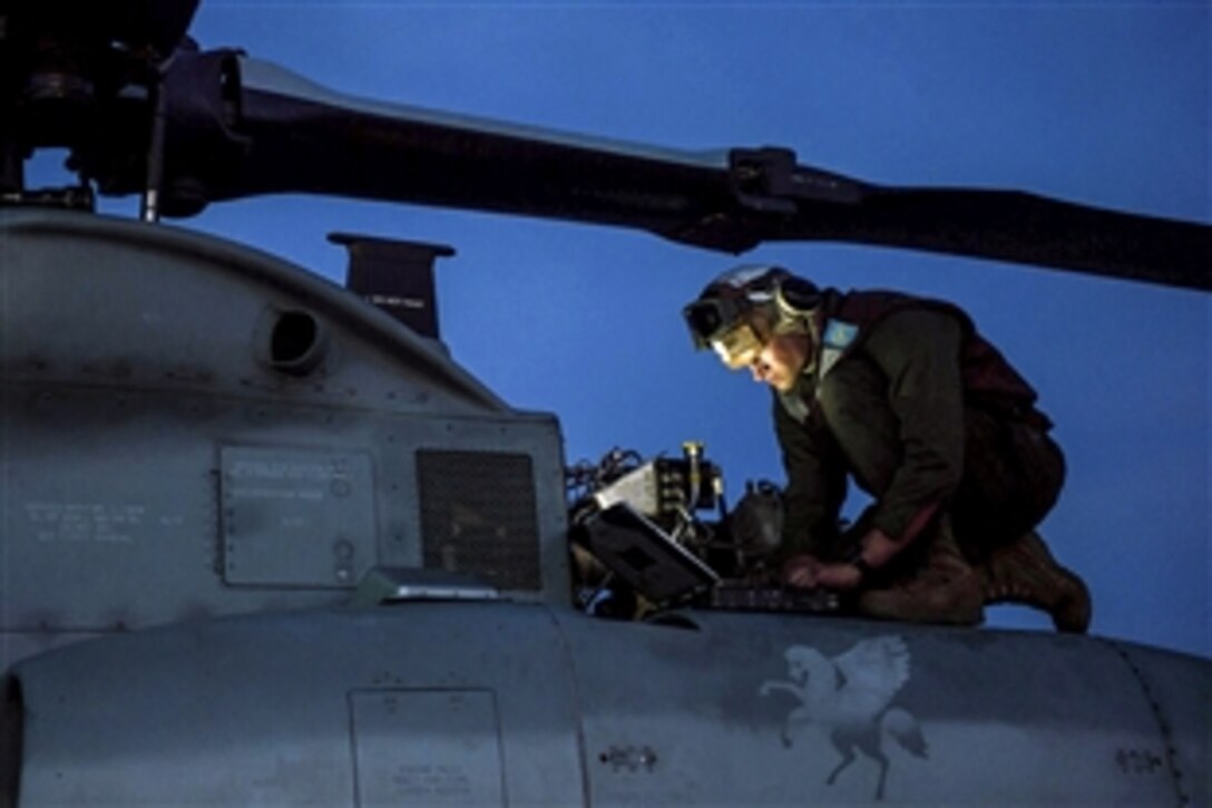A Marine performs maintenance on an AH-1 Cobra helicopter on the flight deck of the amphibious transport dock ship USS Anchorage in the Pacific Ocean, March 16, 2015. The Anchorage participated in a composite training unit exercise. The Marine is assigned to Marine Medium Tiltrotor Squadron 161.
