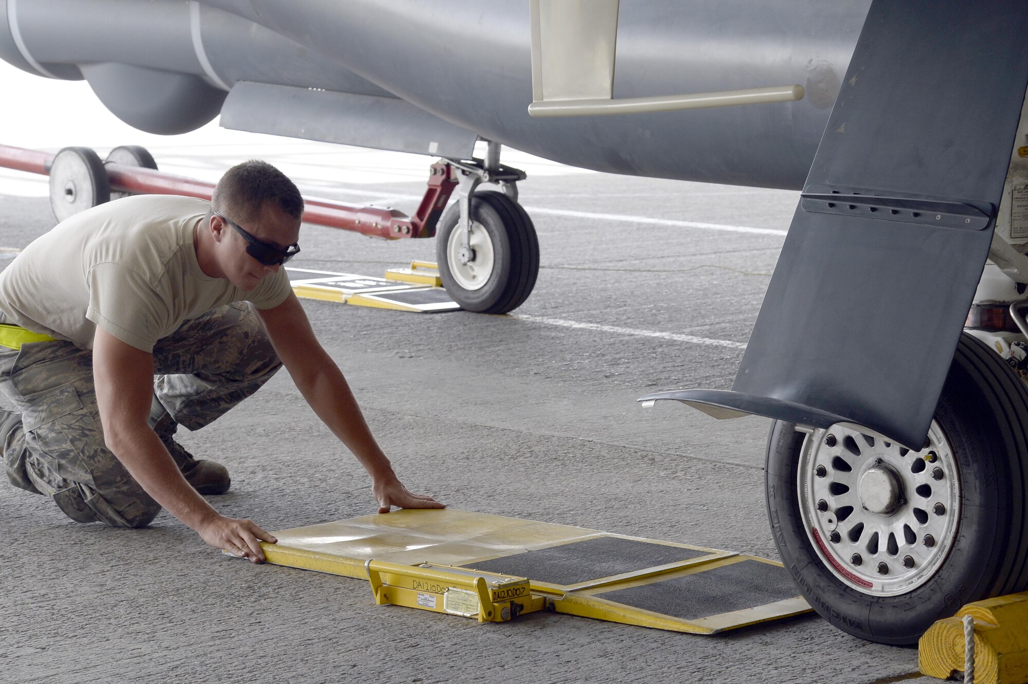 Airman 1st Class Dylan, avionics specialist, places a scale in front of a tire on a RQ-4 Global Hawk at an undisclosed location in Southwest Asia Mar. 8, 2015. The aircraft gets weighed to verify the fuel load and ensure the fuel is properly balanced throughout the aircraft. Dylan is currently deployed from Grand Forks Air Force Base, N.D. (U.S. Air Force photo/Tech. Sgt. Marie Brown)