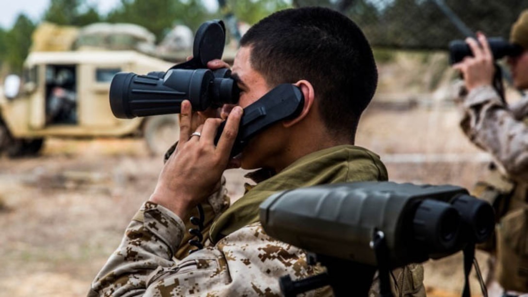 Lance Cpl. Jamie Tenorio, a forward observer with 2nd Battalion, 10th Marine Regiment, 2nd Marine Division communicates with an artillery battery during Exercise Rolling Thunder aboard Fort Bragg, N.C., March 5, 2015. Tenorio sights in with binoculars letting the battery know where the artillery rounds hit.