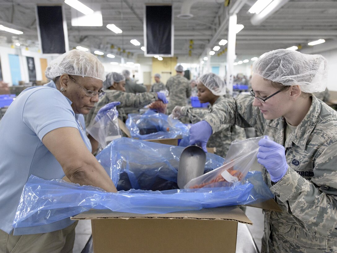 Airman Danica Gendron (right), 71st Comptroller Squadron, packages food at the Regional Food Bank of Oklahoma, March 9, 2015. More than 100 servicemembers teamed up with the Oklahoma City Thunder and packed more than 20,000 pounds of food for Oklahomans in need. (U.S. Air Force photo by David Poe)