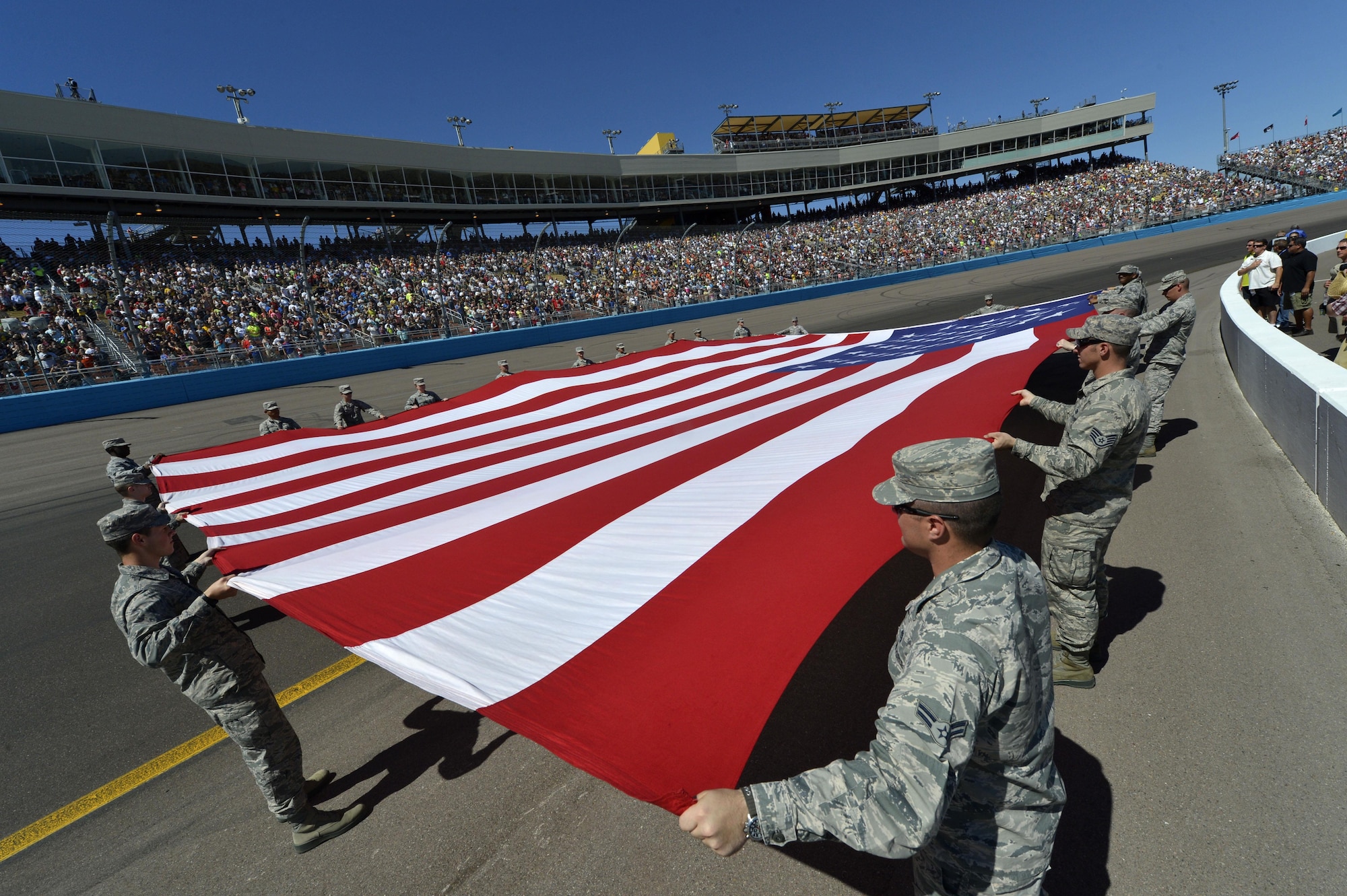 Luke Air Force Base airmen presented a large American flag during the singing of the National Anthem prior to the NASCAR race at the Phoenix International Raceway, Arizona, March 15, 2015. The flag presentation was featured on national television. (U.S. Air Force photo by Senior Airman Devante Williams)