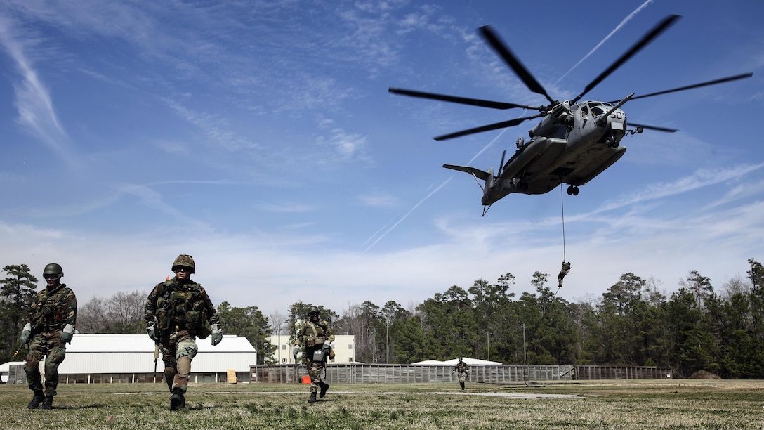 Royal Dutch Marines with the Royal Netherlands Marine Corps run back to a position after fast roping from a CH-53 E Super Stallion at the Expeditionary Operations Training Group compound at Stone Bay aboard Marine Corps Base Camp Lejeune, North Carolina, March 17, 2015. The helicopter hovered 50 feet above the ground with a rope hanging from a hole in the belly of the aircraft, which Royal Marines used to quickly escape and slide down the rope to safely reach the ground.