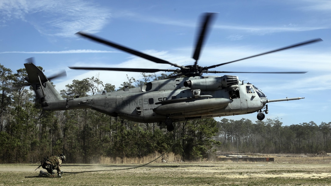 A Royal Dutch Marine with the Royal Netherlands Marine Corps secures a rope attached to a CH-53 E Super Stallion as the helicopter lands at the Expeditionary Operations Training Group compound at Stone Bay aboard Marine Corps Base Camp Lejeune, North Carolina, March 17, 2015. The helicopter hovered 50 feet above the ground with a rope hanging from a hole in the belly of the aircraft, which Royal Marines used to quickly escape and slide down the rope to safely reach the ground. 