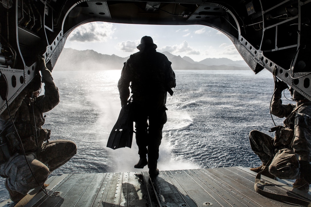 A soldier with Operational Detachment Alpha 1215, 1st Special Forces Group, Joint Base Lewis-McChord, runs off the back of a CH-47F Chinook helicopter while conducting a simulated combat dive mission in the water off of Marine Corps Training Area Bellows, March 16, 2015. The helicopter hovered the ocean and allowed the soldiers to conduct a boat movement leading to reconnaissance of the beach and a raid in the training facility at Bellows. (U.S. Marine Corps photo by Lance Cpl. Brittney Vella/Released)