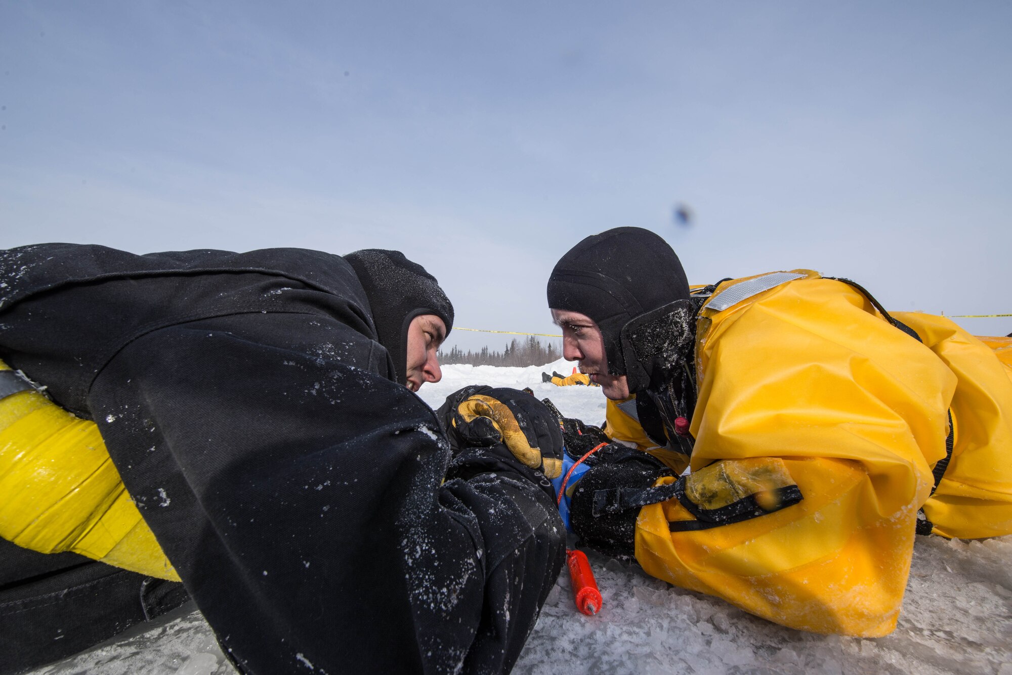 U.S. Air Force Tech. Sgt. Eric Peperissa, a 354th Civil Engineer Squadron firefighter, speaks to a simulated victim trapped in freezing water during training on Eielson Air Force Base, Alaska, March 12, 2015. Fire protection Airmen from the 354th CES train annually to practice rescuing a victim trapped in a broken part of a frozen lake. (U.S. Air Force photo by Staff Sgt. Joshua Turner/Released)