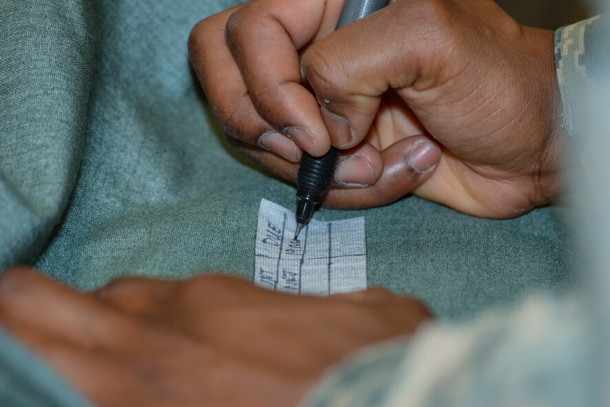 U.S. Air Force Tech. Sgt. Nathaniel Robinson, 23d Operations Support Squadron flight line NCO in charge, fills out an inspection tag on an OTS 600 dry suit which protects aircrew members from cold temperatures if ejected from aircraft over water March 19, 2015, at Moody Air Force Base, Ga. The tag identifies when the inspection was done, who it was done by and when the next inspection is due. (U.S Air Force photo by Airman Greg Nash/Released)