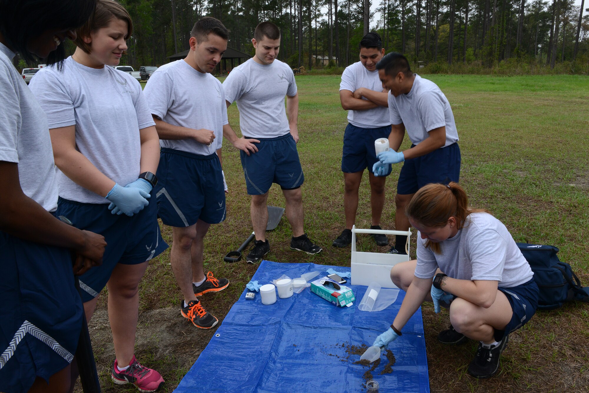 Bioenvironmental Engineering Airmen watch U.S. Air Force Tech. Sgt. Kristi Gillespie, 23d Aerospace Medicine Squadron bioenvironmental technician, right, takes a sample of dirt during an integrated base emergency response capability training March 19, 2015, at Moody Air Force Base, Ga. Gillespie collected the environmental sample to test for chemicals that may be present during the training scenario. (U.S. Air Force photo by Airman 1st Class Kathleen D. Bryant)