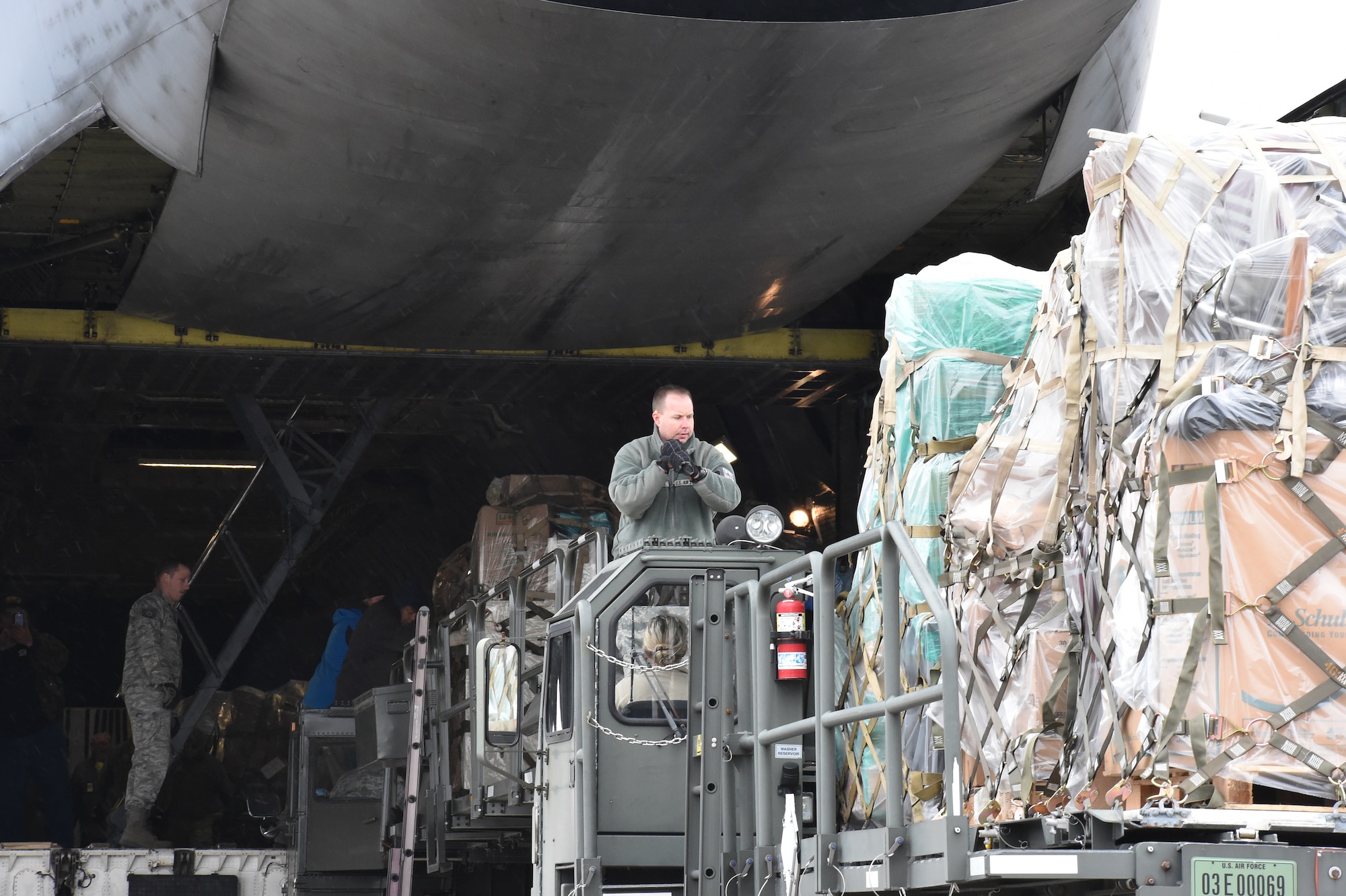 Senior Master Sgt. Kevin Massie, superintendent of the 76th Aerial Port Squadron (APS), directs a K-loader cargo transport vehicle up to the rear of a C-5 Super Galaxy cargo aircraft from Dover Air Force Base, Delaware on the flight line here, March 20, 2015. Massie and other Airmen from APS packaged approximately 90 thousand pounds of cargo onto Air Force pallets for transport to Guatemala via the Denton Program. The cargo, which included school supplies, medical items and furniture, was collected by Austintown based Mission of Love charity. U.S. Air Force photo/Eric M. White.