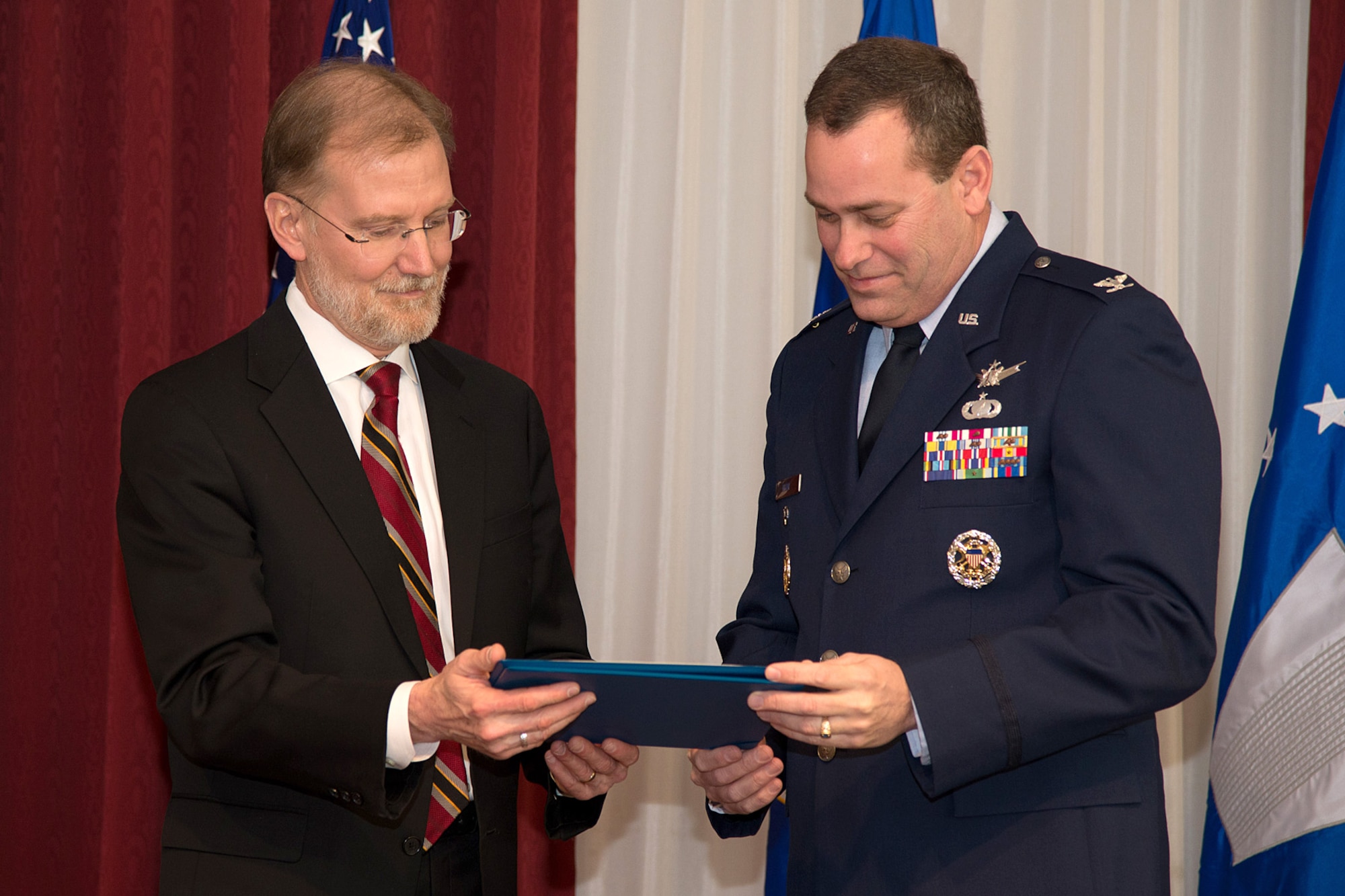 Steve Wert, Battle Management program executive officer, presents Col. Gregg A. Kline a certificate upon the occasion of his retirement from the U.S. Air Force during a ceremony at the Minuteman Commons, March 13. Kline, who had served as the Battle Management Operational Command And Control Division chief, retired after more than 25 of years in the Air Force. (U.S. Air Force photo by Mark Herlihy)