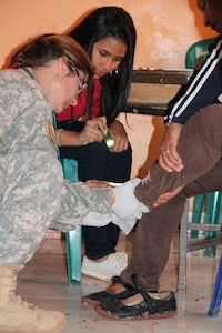 Maj. Rhonda Dyer, Joint Task Force Bravo Medical Element community health nurse, checks the foot of a Honduran local during a Medical Readiness Training Exercise, March 11-15, 2015. Joint Task Force-Bravo's Medical Element (MEDEL), with support from JTF-Bravo’s Joint Security Forces and Army Forces Battalion, partnered with the Honduran Ministry of Health and the Honduran military to provide medical care to more than 5,352 people and performed 11 surgeries over three days in the Department of Copan and Lempira, Honduras during a Mobile Surgical Team (MST), Medical Readiness Training Exercise (MEDRETE), and a Medical Partnership Exercise (MPE). (Photo by U.S. Army Sgt. Stephanie Tucker)