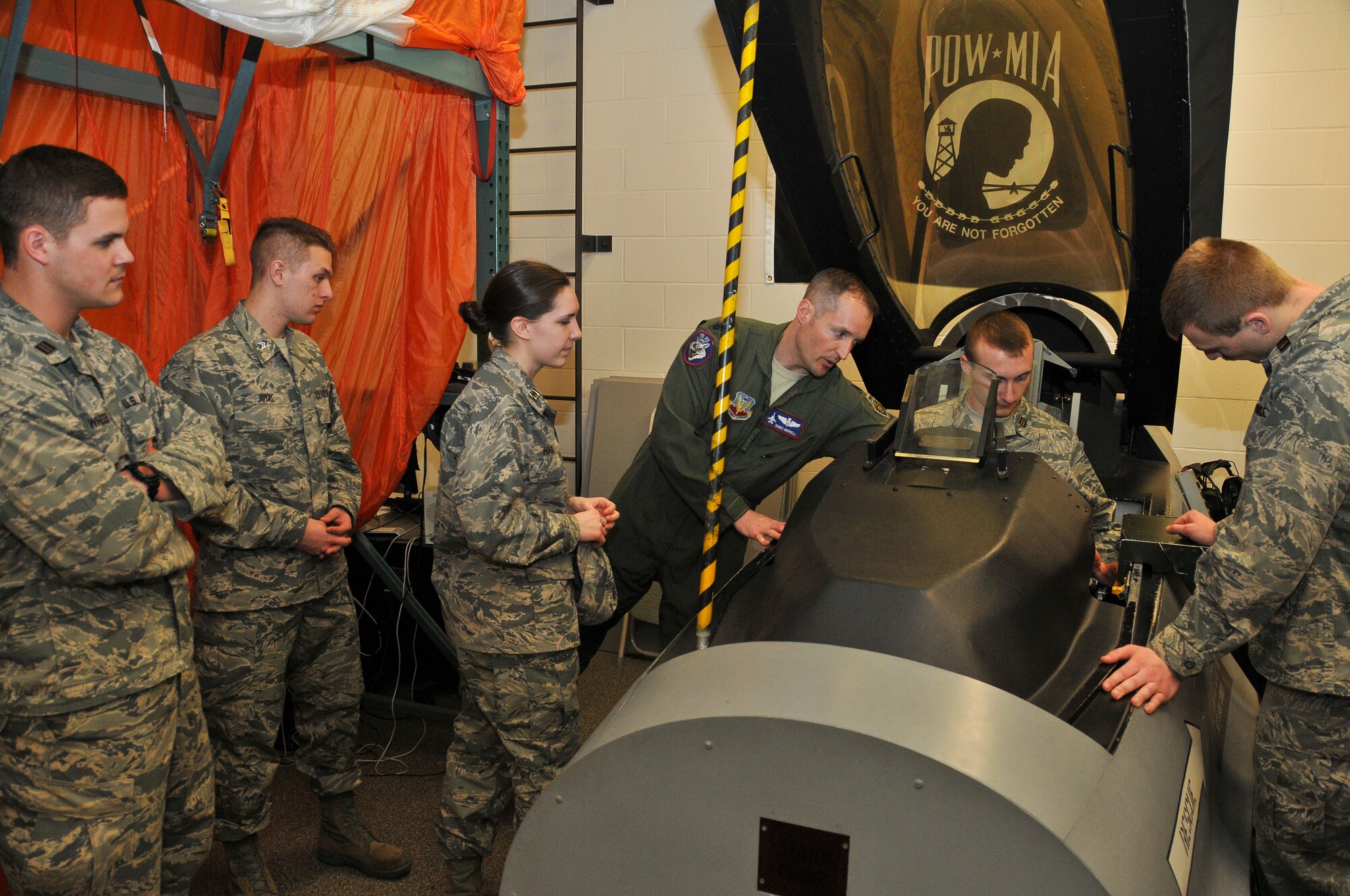 Lt. Col. Mark Morrell, 114th Operations Support Squadron commander, explains the controls of the pilot ejection (egress) trainer on the F-16 to the South Dakota State University ROTC cadets at Joe Foss Field, S.D., March 19, 2015. The students toured the 114th Fighter Wing and were briefed about the many roles and specialized fields that make up the South Dakota Air National Guard.(National Guard photo by Staff Sgt. Luke Olson/Released)