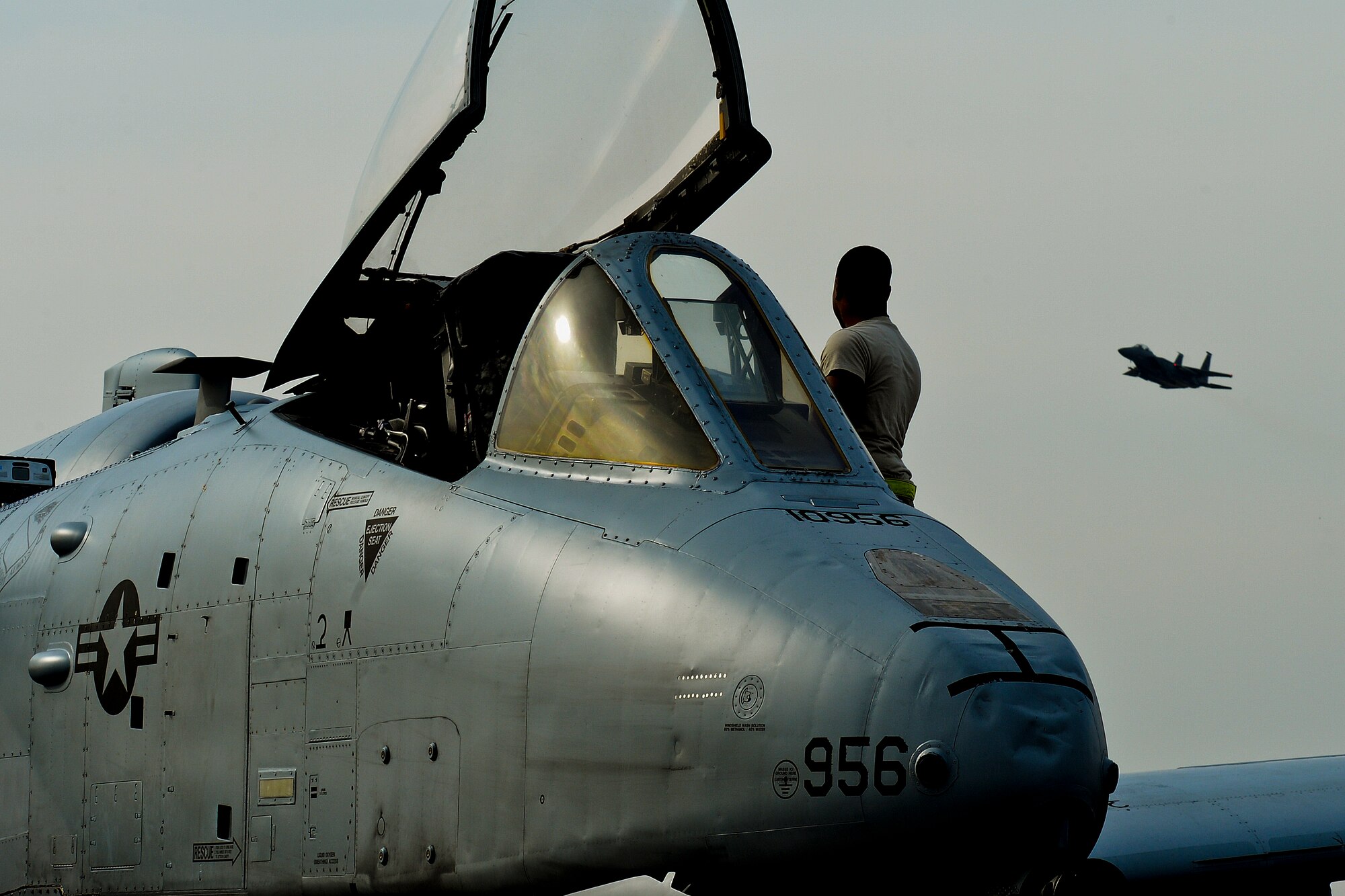 An A-10C Thunderbolt II sits on the flightline as an F-15E Strike Eagle takes off at Royal Air Force Lakenheath, England, March 13, 2015. The A-10s and 355th Fighter Wing Airmen are deployed out of Davis-Monthan Air Force Base, Ariz., as part of a Theater Security Package in support of Operation Atlantic Resolve. While visiting RAF Lakenheath for five days, they conducted training alongside NATO allies to strengthen interoperability and demonstrate U.S. commitment to the security and stability of Europe. (U.S. Air Force photo by Airman 1st Class Trevor T. McBride/Released)
