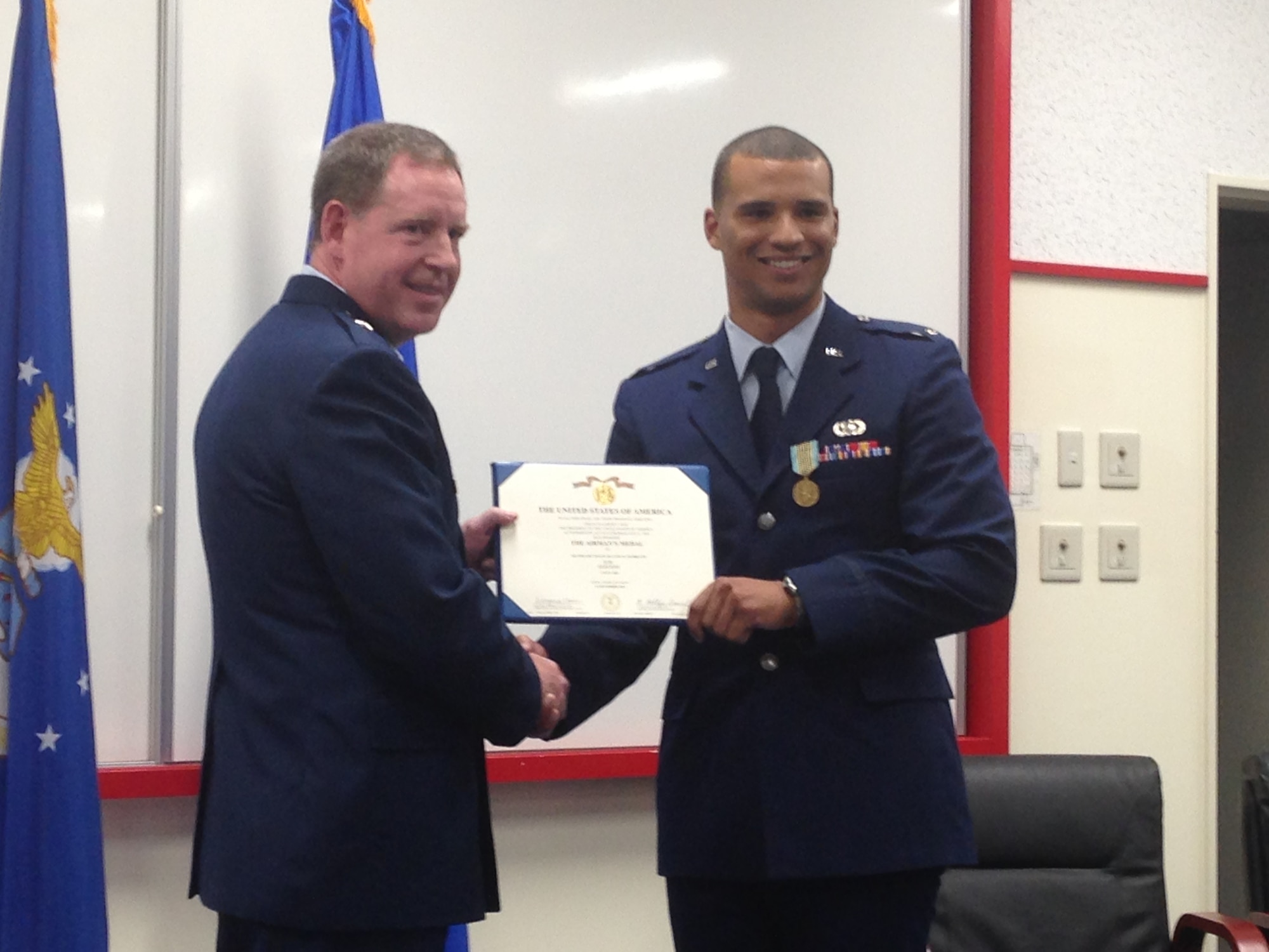 U.S. Air Force Brig. Gen. James B. Hecker, 18th Wing commander, presents 1st Lt. Dayton Gilbreath, 18th Contracting Squadron contracting administrator, with a certificate to accompany his Airman’s Medal on Kadena Air Base, Japan, March 20, 2015. Gilbreath was awarded the medal for rescuing an Airman who jumped overboard from a sailing ship in the Adriatic Sea July 3, 2012. (U.S. Air Force photo by Staff Sgt. Amber Jacobs)