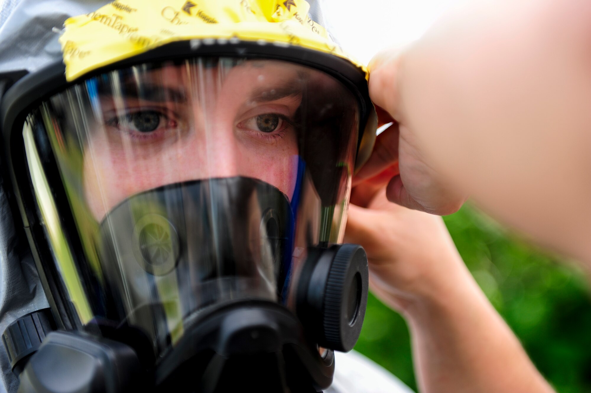 U.S. Air Force Airman 1st Class Nathanael Nederman, 18th Civil Engineer Squadron Readiness and Emergency Management Flight technician, dons an MSA Firehawk Mask with the help of a wingman during an Integrated Base Emergency Response Capabilities Training exercise March 18, 2015, on Kadena Air Base, Japan. Nederman was part of a decontamination team who helped to clean members who assessed an environment for potential biohazards. (U.S. Air Force photo by Airman 1st Class John Linzmeier)