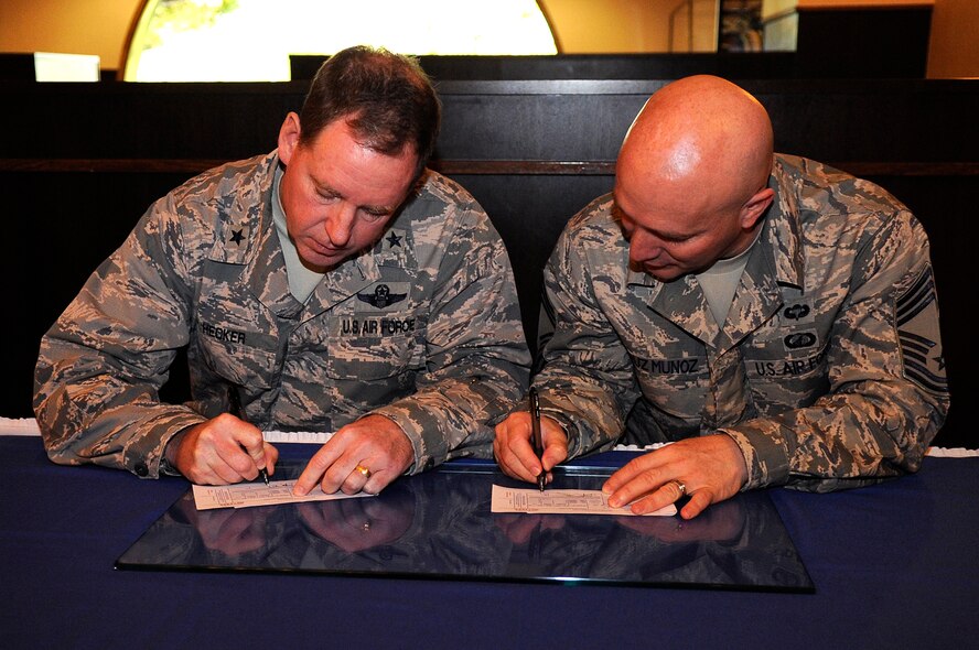 U.S. Air Force Brig. Gen. James Hecker, 18th Wing commander (left), and Chief Master Sgt. Anthony Cruz-Munoz, 18th Wing interim command chief, fill out Air Force Assistance Fund pledges during the AFAF kick-off on Kadena Air Base, Japan, March 23, 2015. The Air Force Assistance Fund is a program designed to raise money to assist Airmen during times of need. (U.S. Air Force photo by Staff Sgt. Marcus Morris)