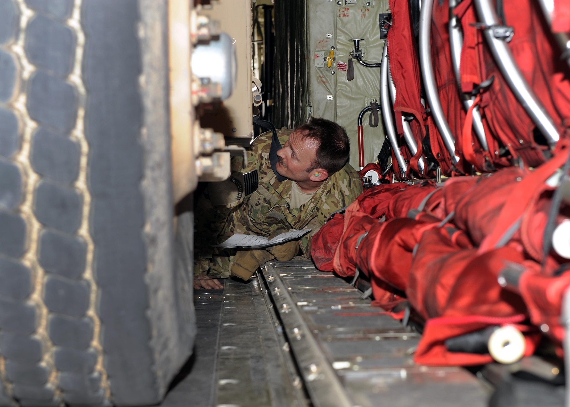 U.S. Air Force Senior Master Sgt. Jason Buttke, 774th Expeditionary Airlift Squadron loadmaster, maneuvers from the back of the cargo compartment of a C-130J Super Hercules aircraft to the front while inspecting the tie-downs securing an R-11 fuel truck to the aircraft March 15, 2015. The ability to forward deploy mission critical equipment, such as the R-11, to key sites throughout the AOR is more imperative than ever before as the Air Force reduces its footprint in the region. (U.S. Air Force photo by Staff Sgt. Whitney Amstutz)