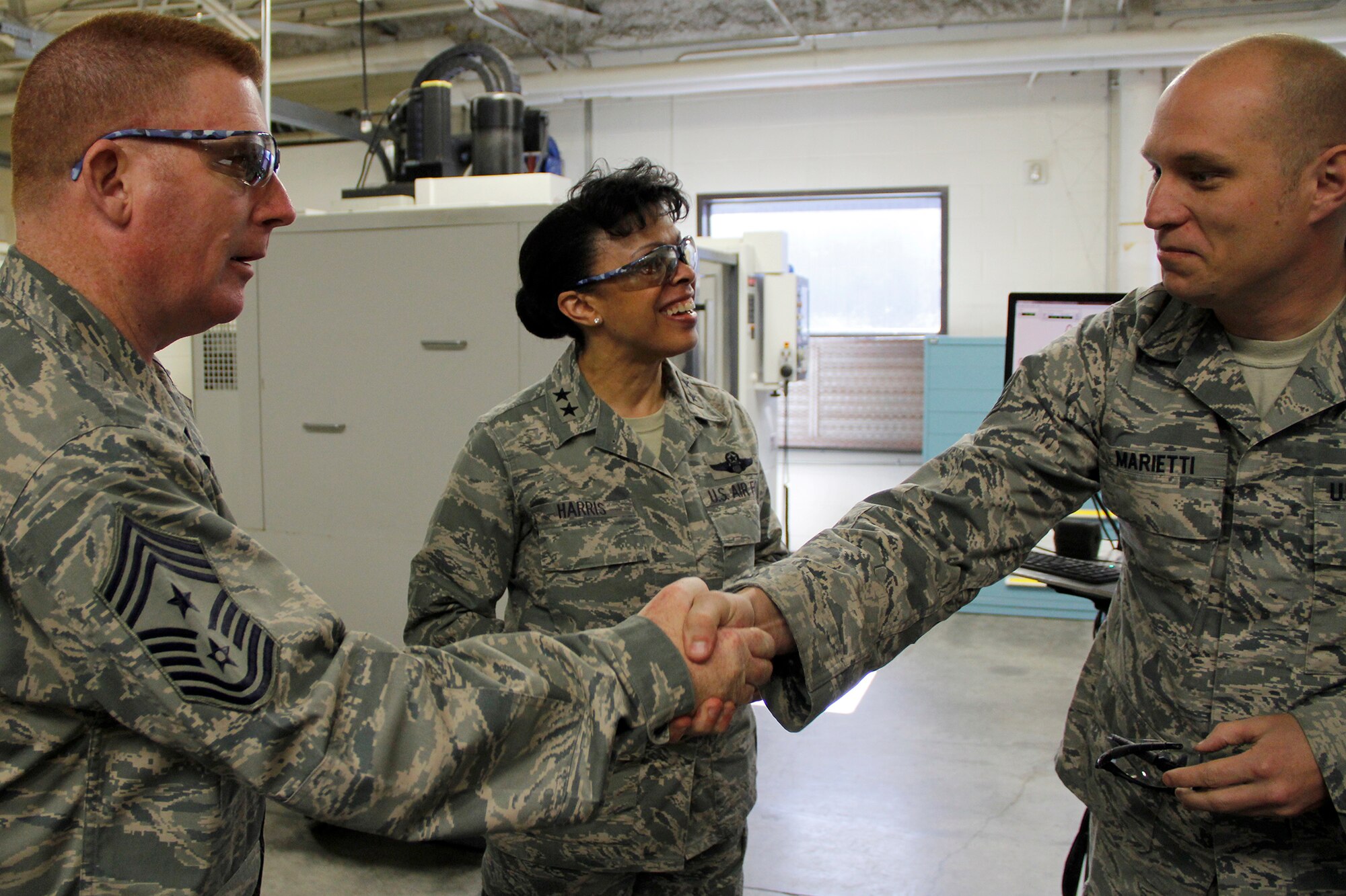 Chief Master Sgt. Michael F. Thorpe, shakes hands with Staff Sgt. Ian Marietti, 52nd Airlift Squadron, aircraft metals technician, as Maj. Gen. Stayce D. Harris looks on March 7 here. The 302nd Maintenance Squadron, metals technology shop demonstrated their manufacturing capabilities to Maj. Gen. Stayce D. Harris, 22nd Air Force commander, and Chief Master Sgt. Michael F. Thorpe, 22nd Air Force command chief, during their visit. (U.S. Air Force photo/Staff Sgt. Nathan Federico)